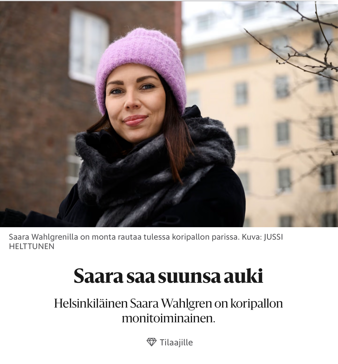 Henkilö talvivaatteissa, pinkki talvitakki ja harmaa ja musta huivi, ulkona kaupunkimaisemassa, talvisessa säässä.