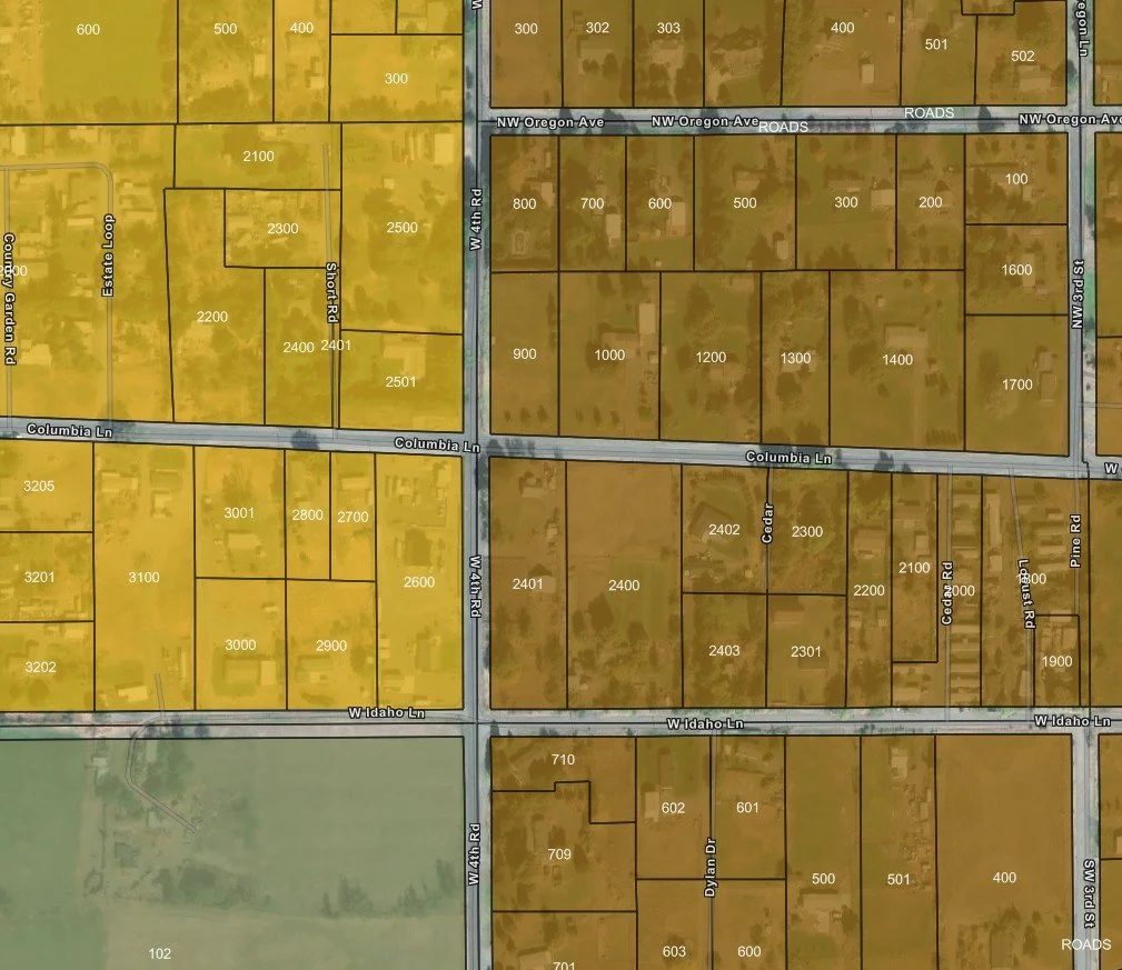 Map showing a grid of parcels with numbers, streets labeled: Columbia Ln, NW Oregon Ave, W 4th Rd, W Idaho Ln, W 3rd St, and others. The parcels are marked with property numbers and borders.
