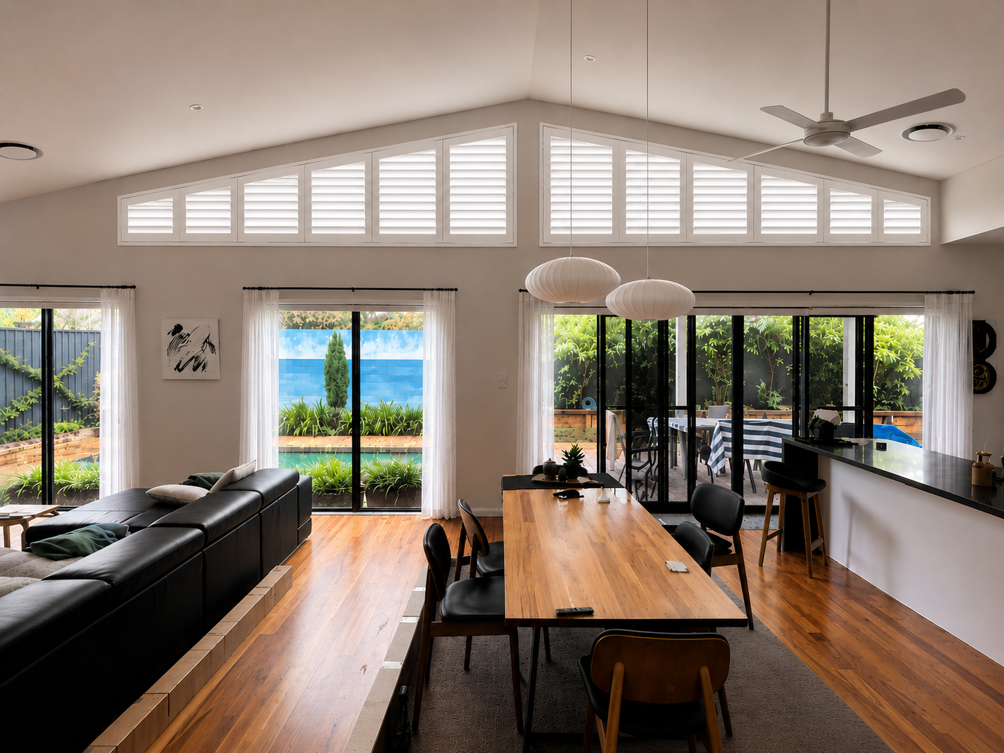 AI preview showing Ecosmart plantation shutters with 12 panels across shaped windows in an Oran Park living area.
