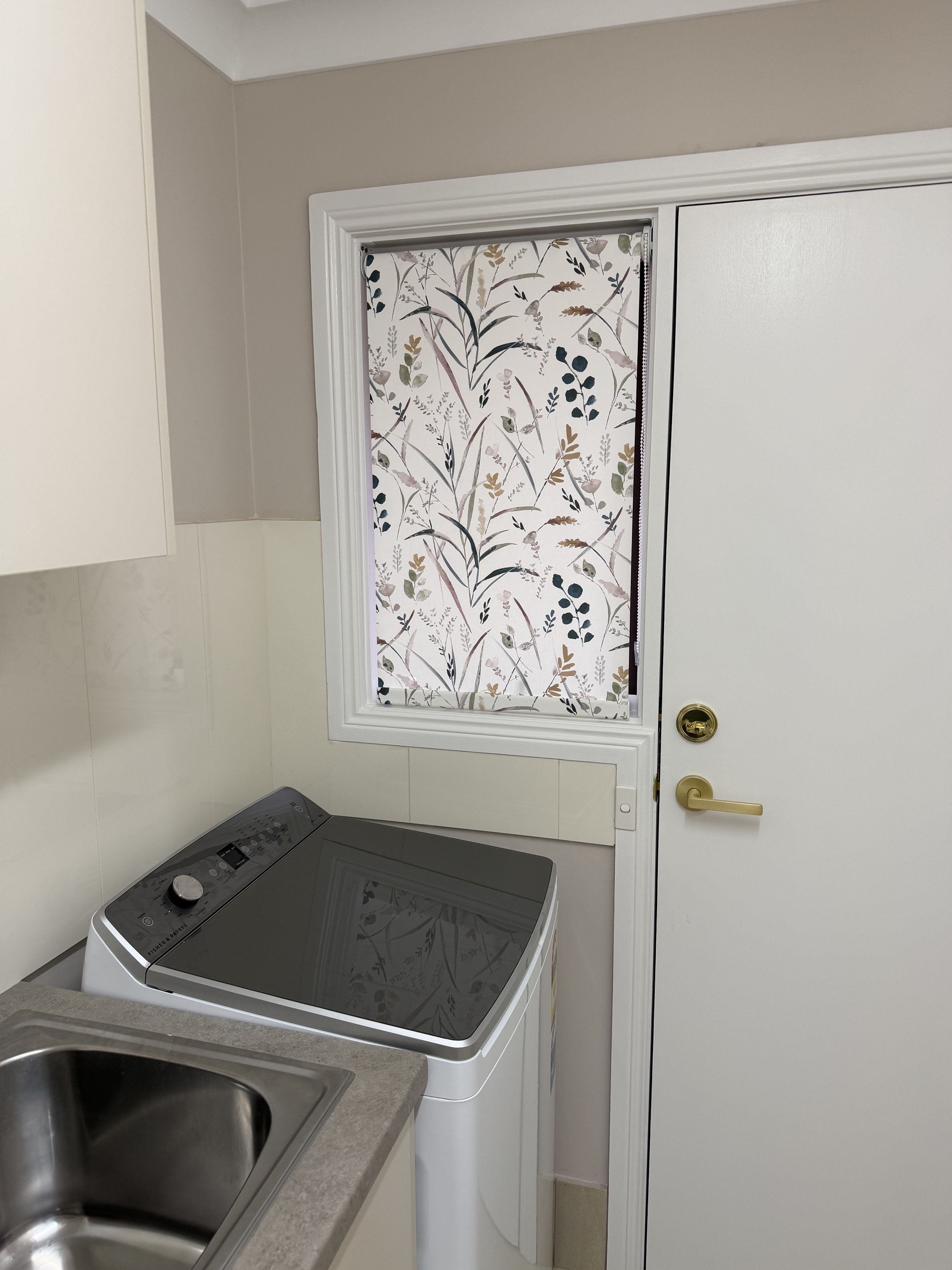Pattern fabric roller blind fully lowered in laundry room