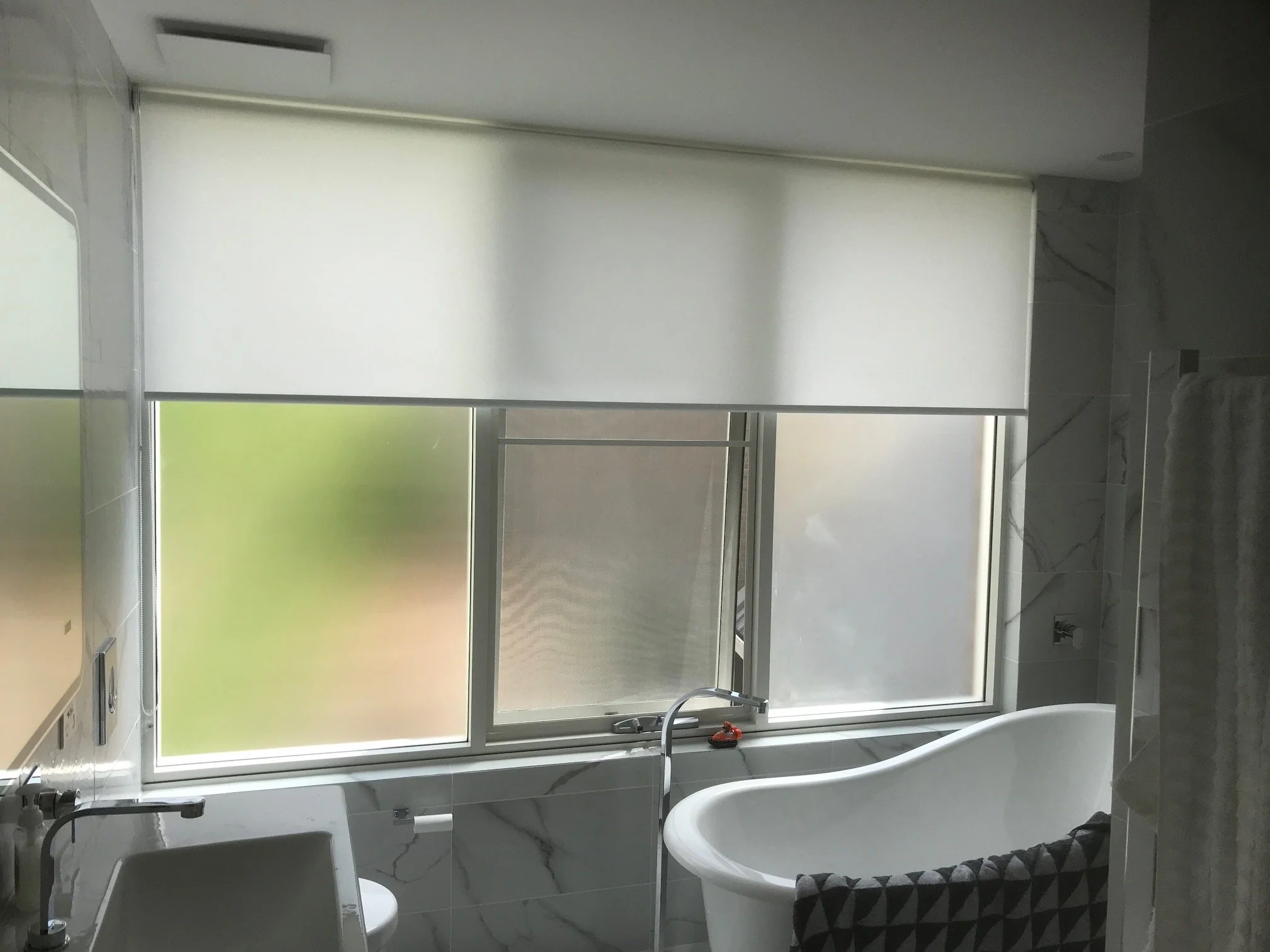 Light filtering roller blinds installed in a modern bathroom window