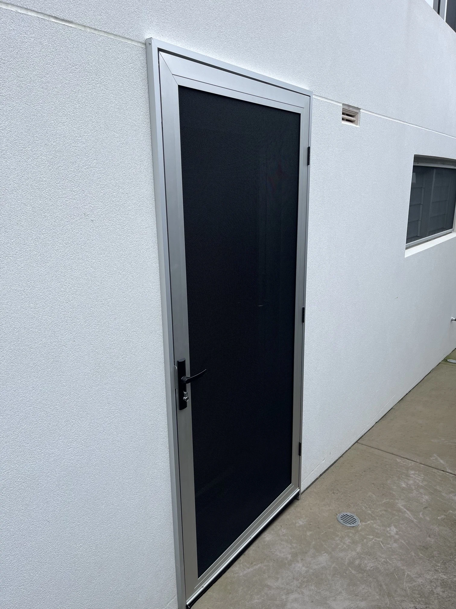 Amplimesh Security Door in anodised silver colour with frame buildout to clear main door lock.