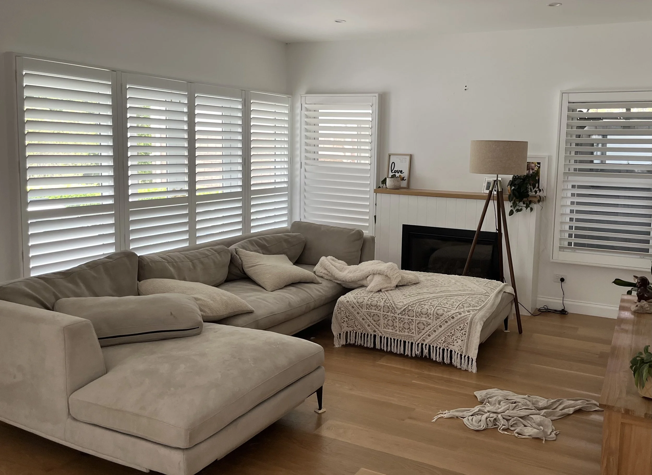 White plantation shutters installed throughout a modern living room in Camden