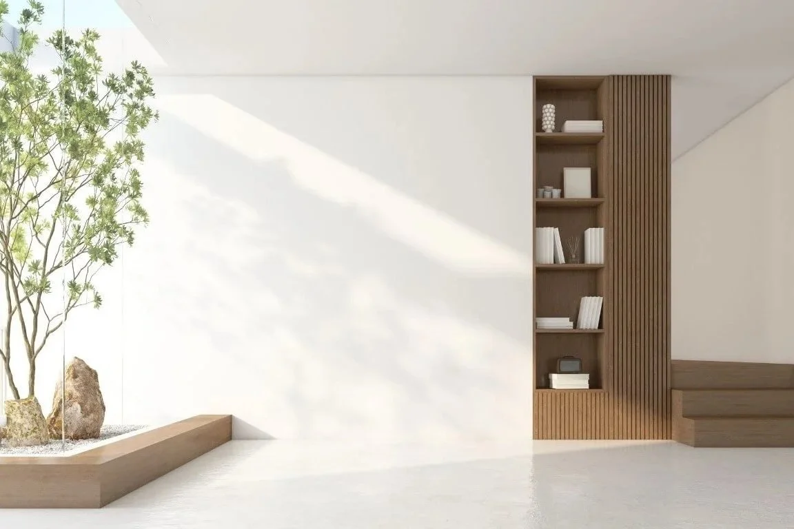 Intérieur minimaliste avec un arbre dans un coffrage en bois, étagère en bois avec des livres, objets décoratifs, dans un espace lumineux.