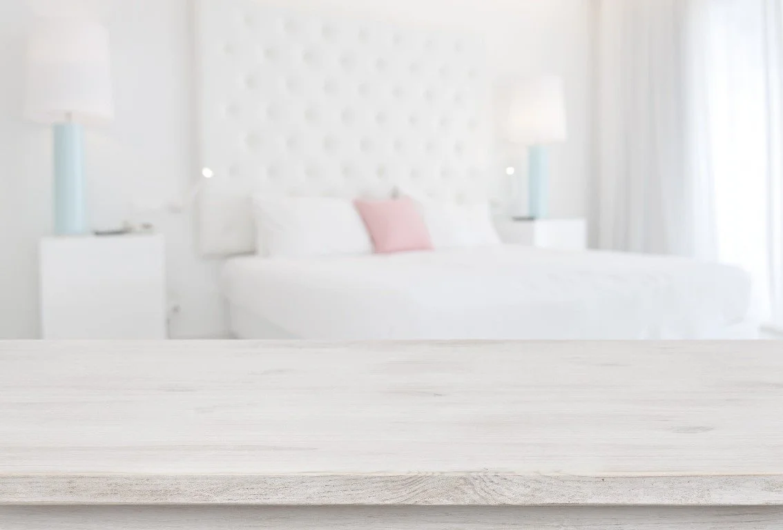 Chambre à coucher avec lit blanc, deux tables de nuit, lampes et coussin rose, style moderne et lumineux.