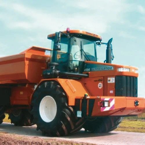 Caminhão de escavadeira agrícola de cor laranja em um campo ao ar livre.