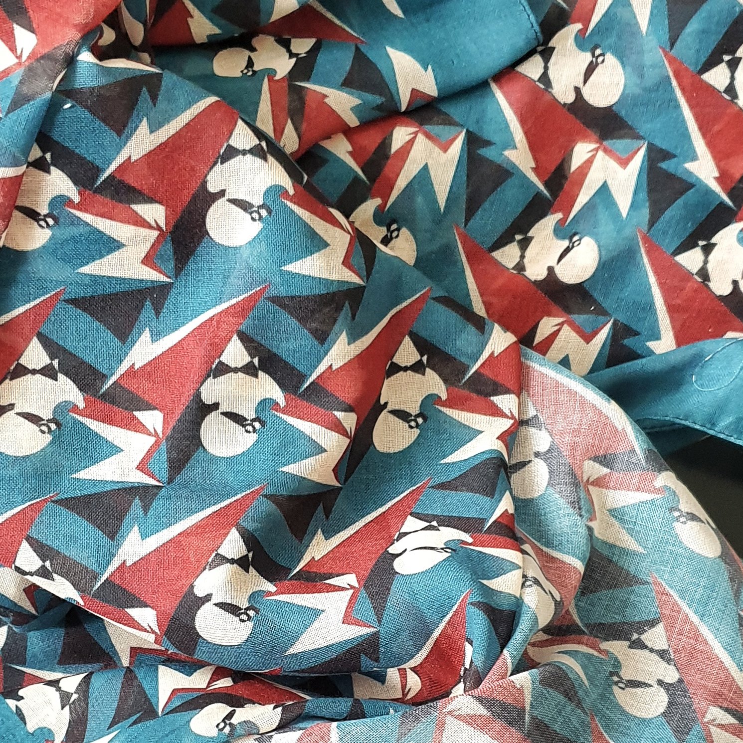 Fabric with a pattern of stylized marinetti portraits and lightning bolts in red, black, white, and blue colors.