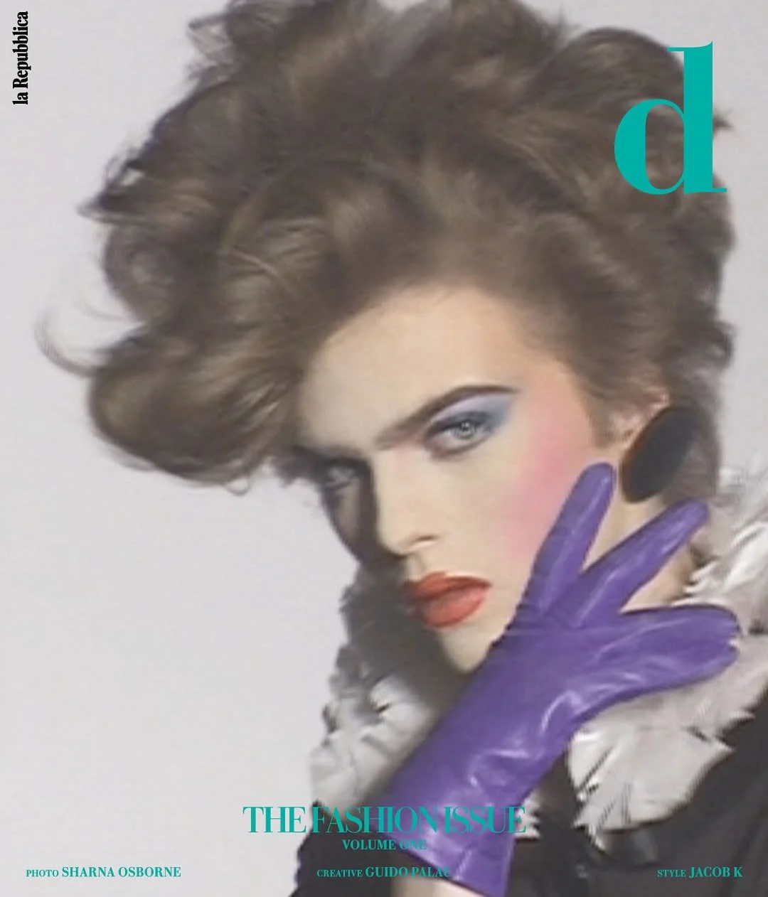 Cover of a fashion magazine featuring a woman with elaborate hair, wearing purple gloves, bold makeup, and large earrings. The magazine title is partially visible with the letters 'd' and the subtitle 'THE FASHION ISSUE VOLUME 09+'.