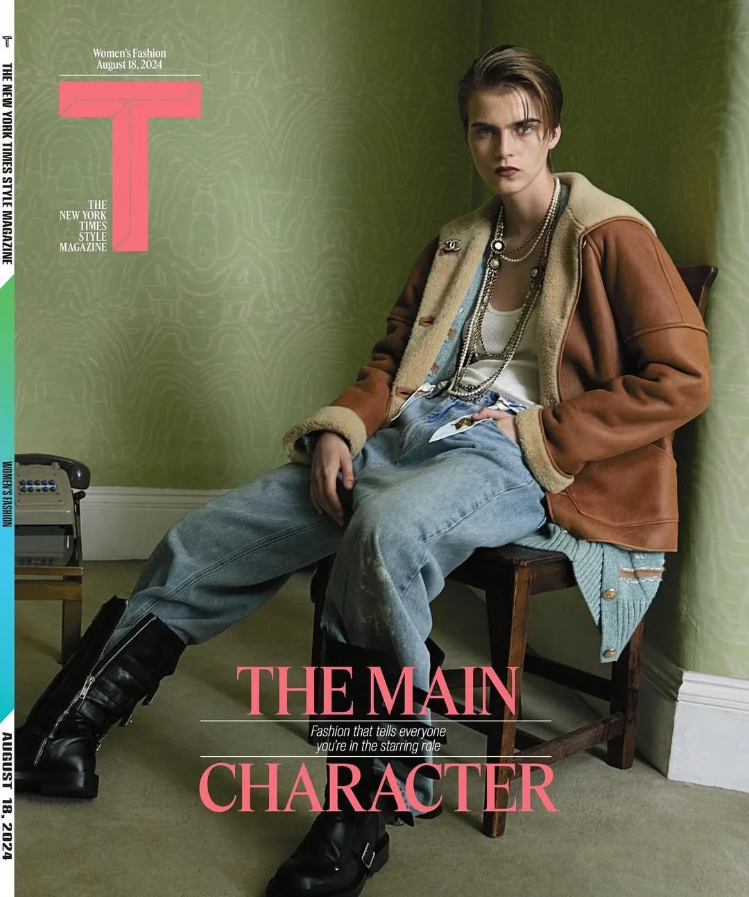 Cover of Women's Fashion magazine from August 18, 2024, featuring a young woman sitting on a chair in a room with green wallpaper, wearing a brown and beige shearling jacket, layered necklaces, a white tank top, baggy jeans, and black boots, with the