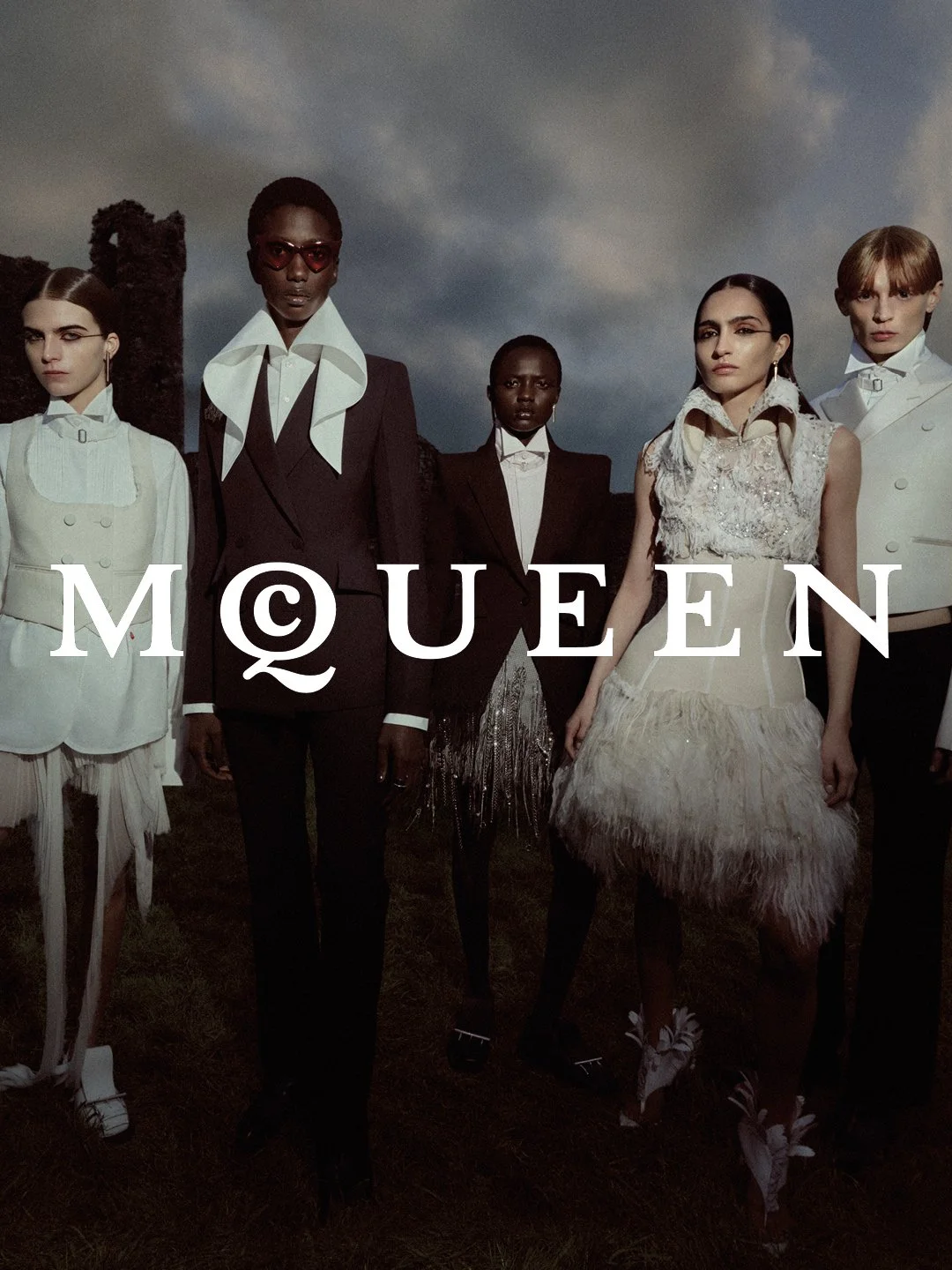 Fashion models dressed in high couture clothing standing outdoors under a cloudy sky, with the 'MQÜEN' brand logo overlayed.