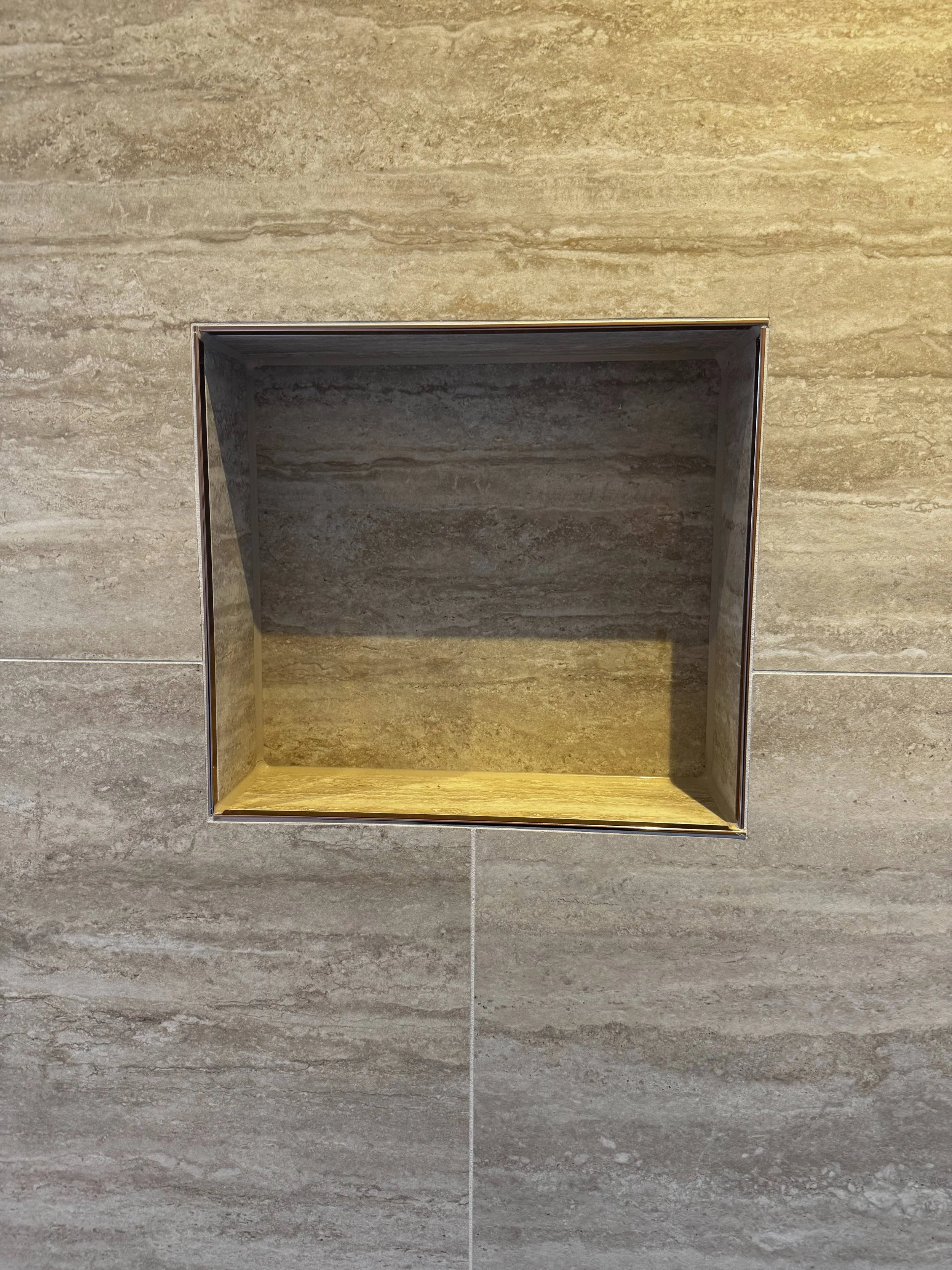 Leeg ingebouwd nis in een muur met beige en bruin gemarmerd tegelpatroon.