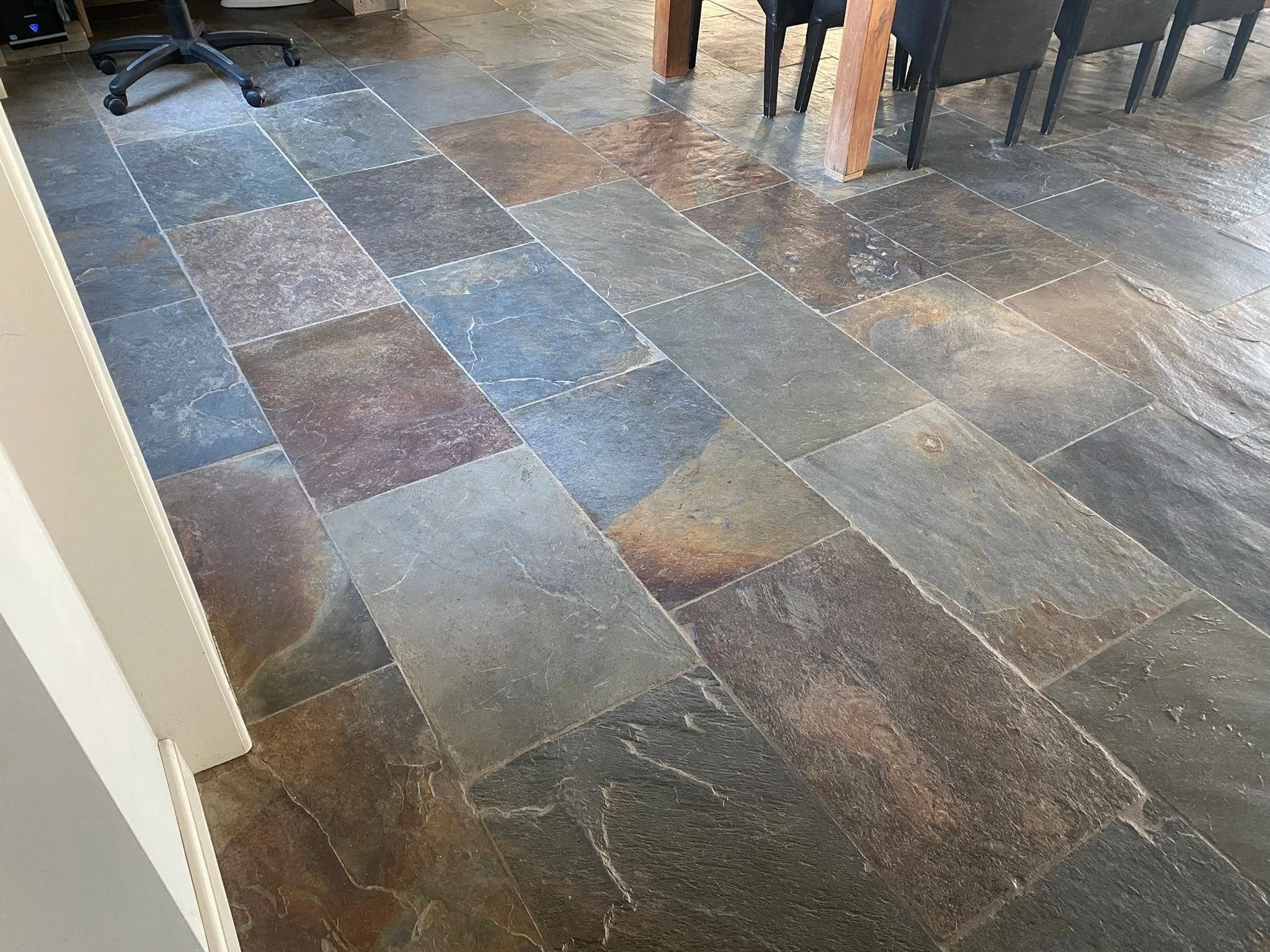 Gekleurde natuurstenen vloer met rechthoekige tegels, in een kamer met eetstoel en tafel.