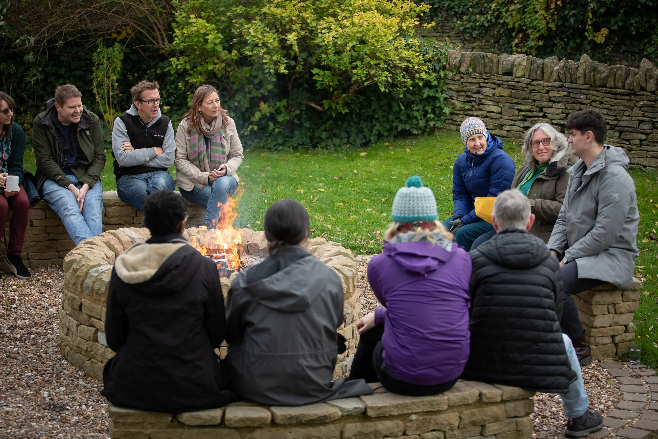 A group sit by a camp fire having a discussion
