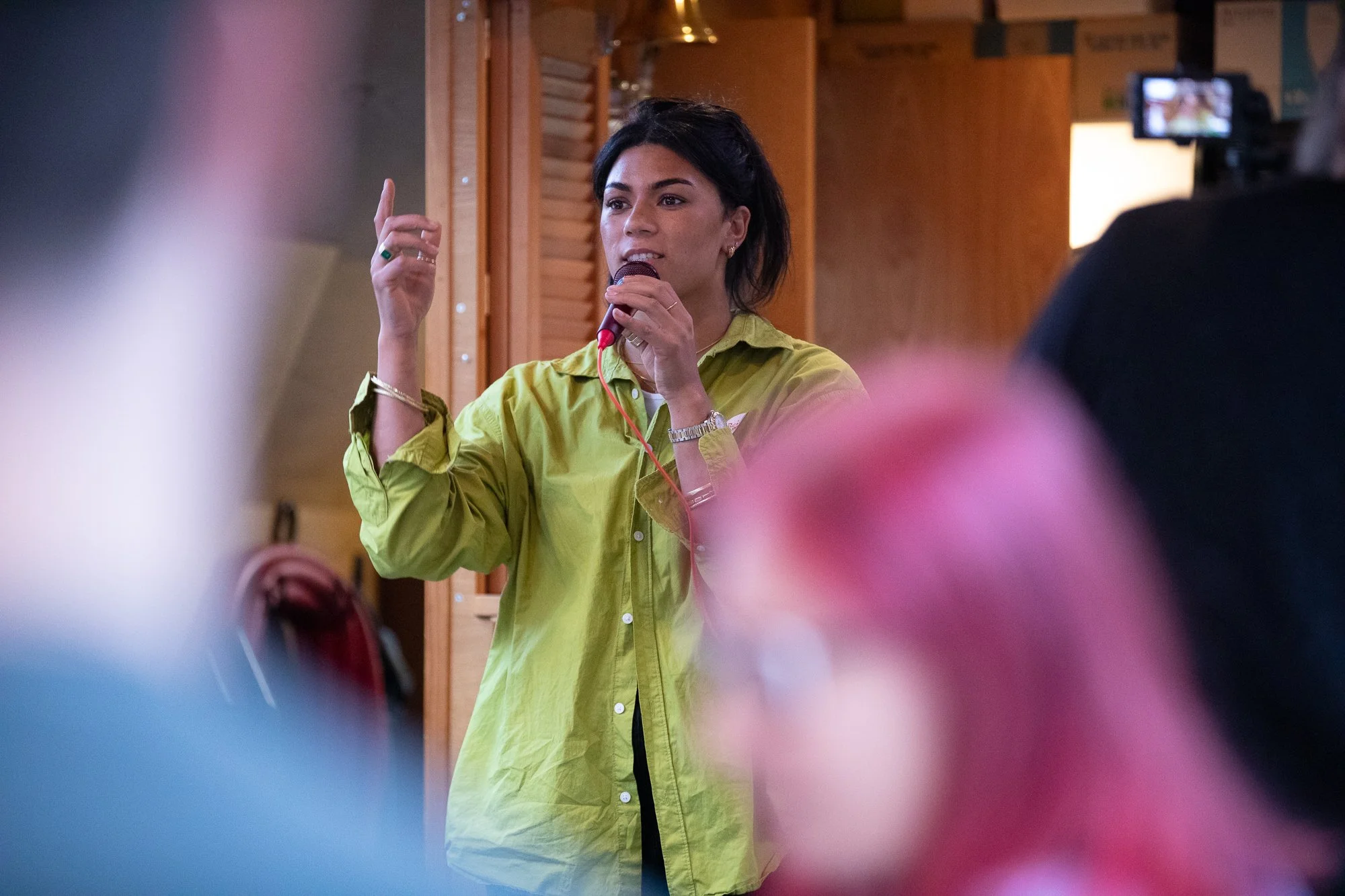 A woman in a green top speaks into a microphone