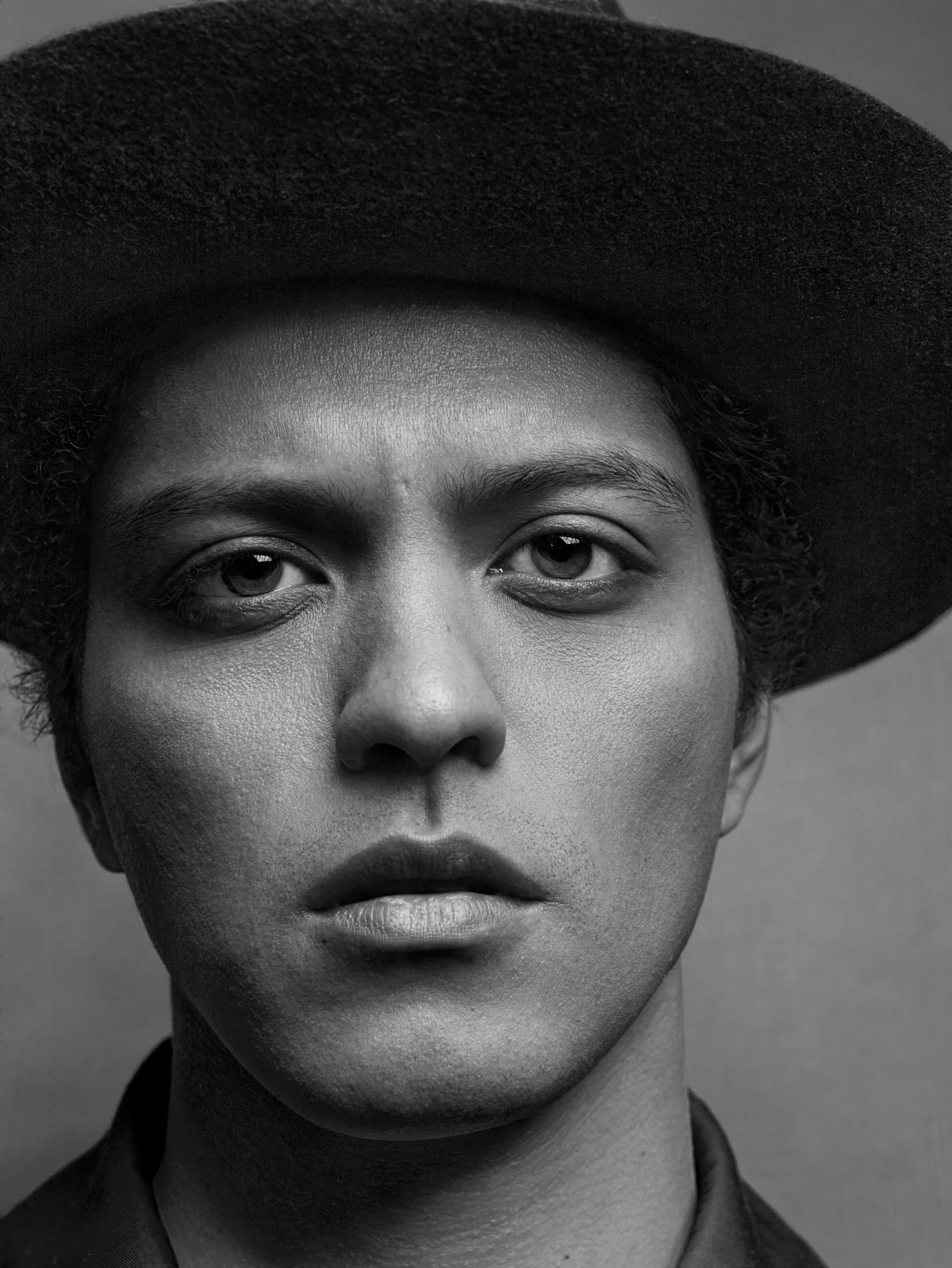 Black and white close-up portrait of a person wearing a wide-brimmed hat.