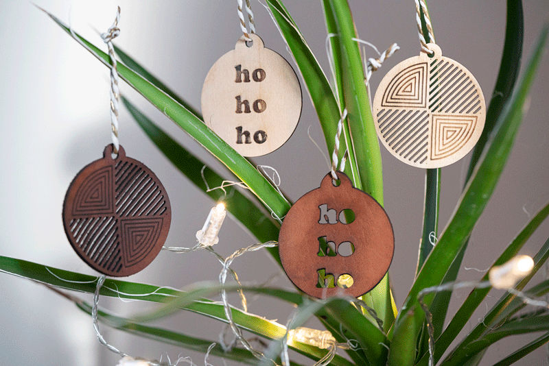 Lasergeschnittene Weihnachtsanhänger aus Holz und Leder mit ho ho ho Schriftzug und geometrischen Mustern