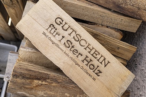 Gutschein für einen Ster Holz als Lasergravur auf Brennholz, kreative Geschenkidee