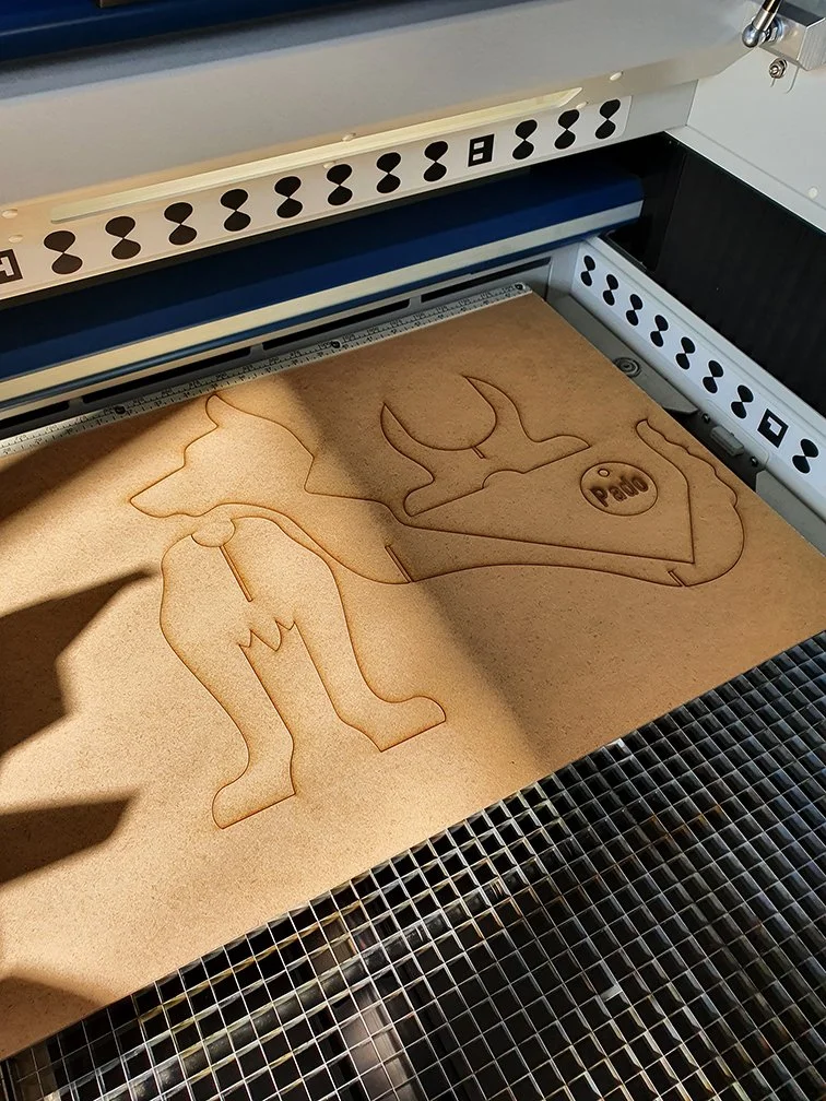 Lasercutter schneidet Hundefigur mit graviertem Namen aus MDF Platte in der Werkstatt von IRIX Design