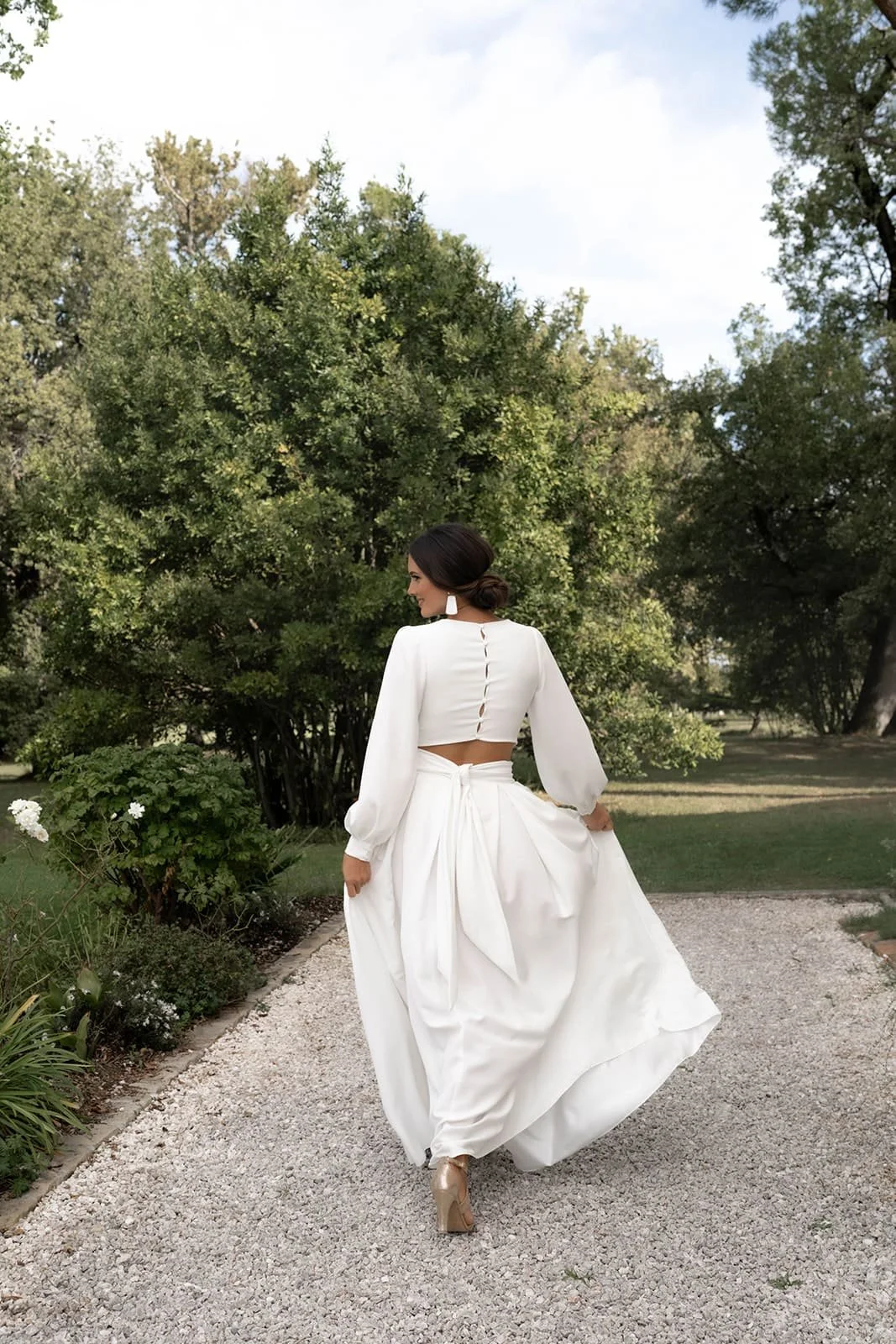 Une femme habillée en robe blanche dans un jardin verdoyant.