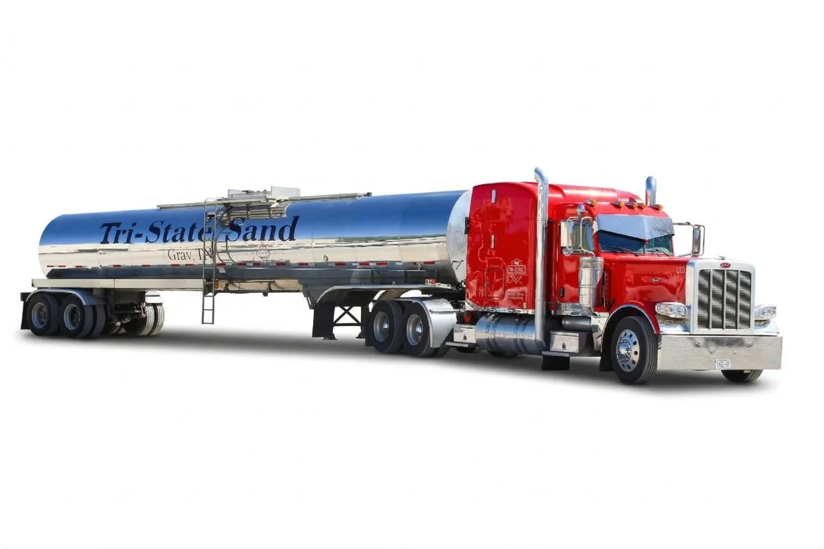 A large red semi-truck with a shiny silver tank trailer labeled 'Tri-State Sand' on a white background.