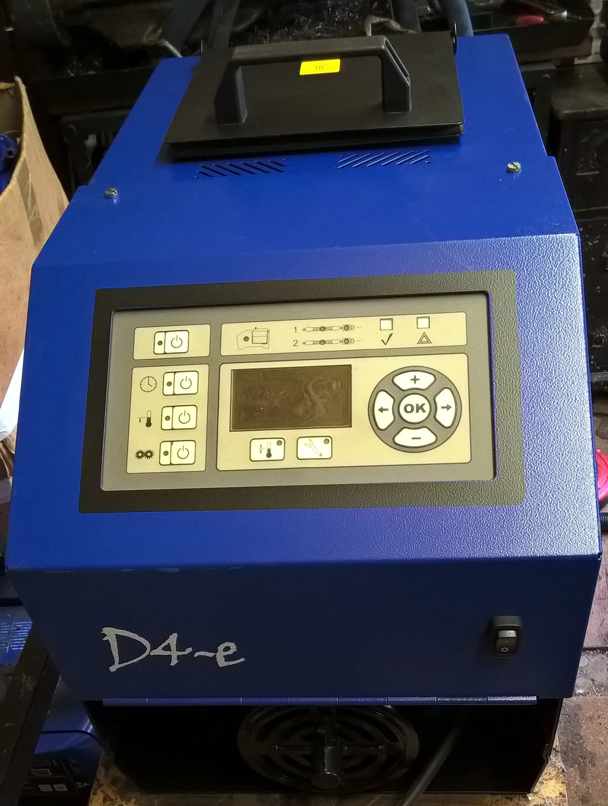 A blue electronic device with a digital display, various buttons, and a black handle on top. The device appears to be industrial or laboratory equipment, with a label indicating it is a conveyor dryer, model D4-e.