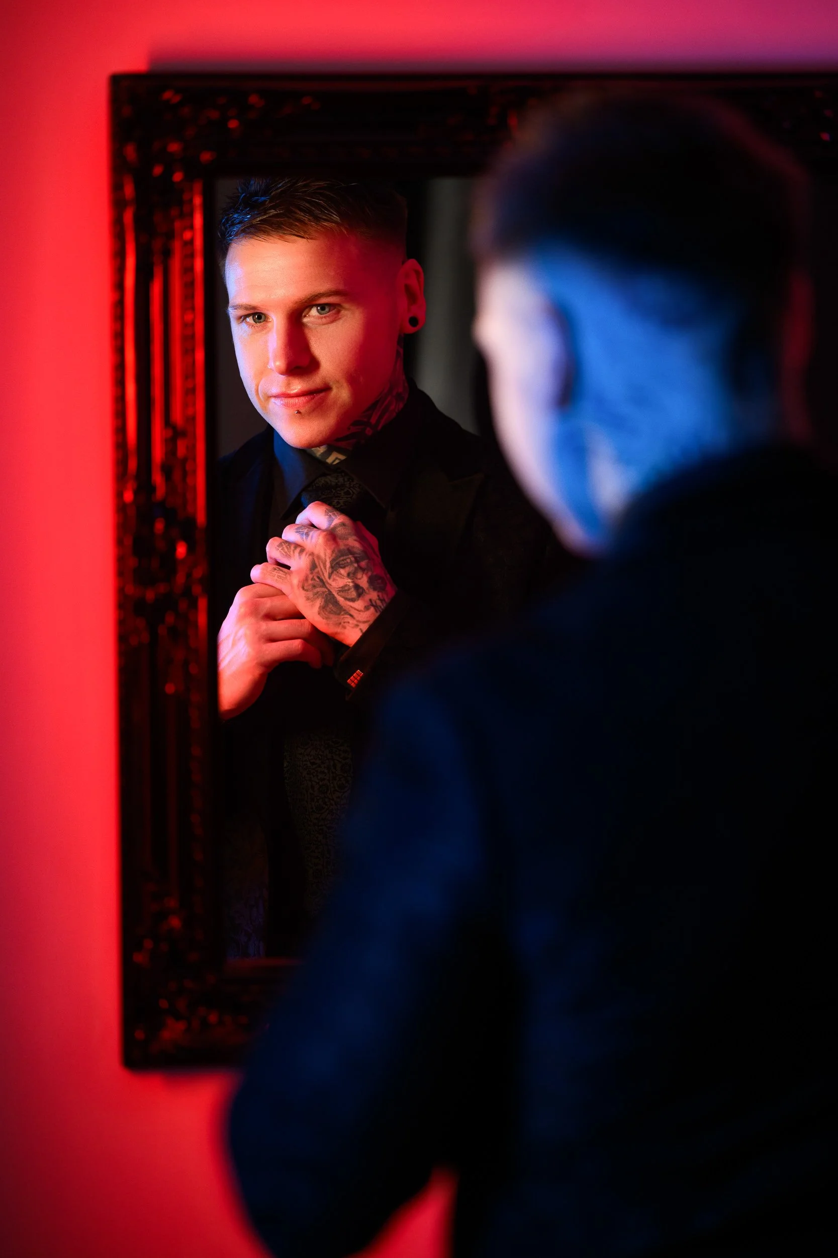 Portrait Photography Ireland – groom adjusting tie in mirror with cinematic lighting