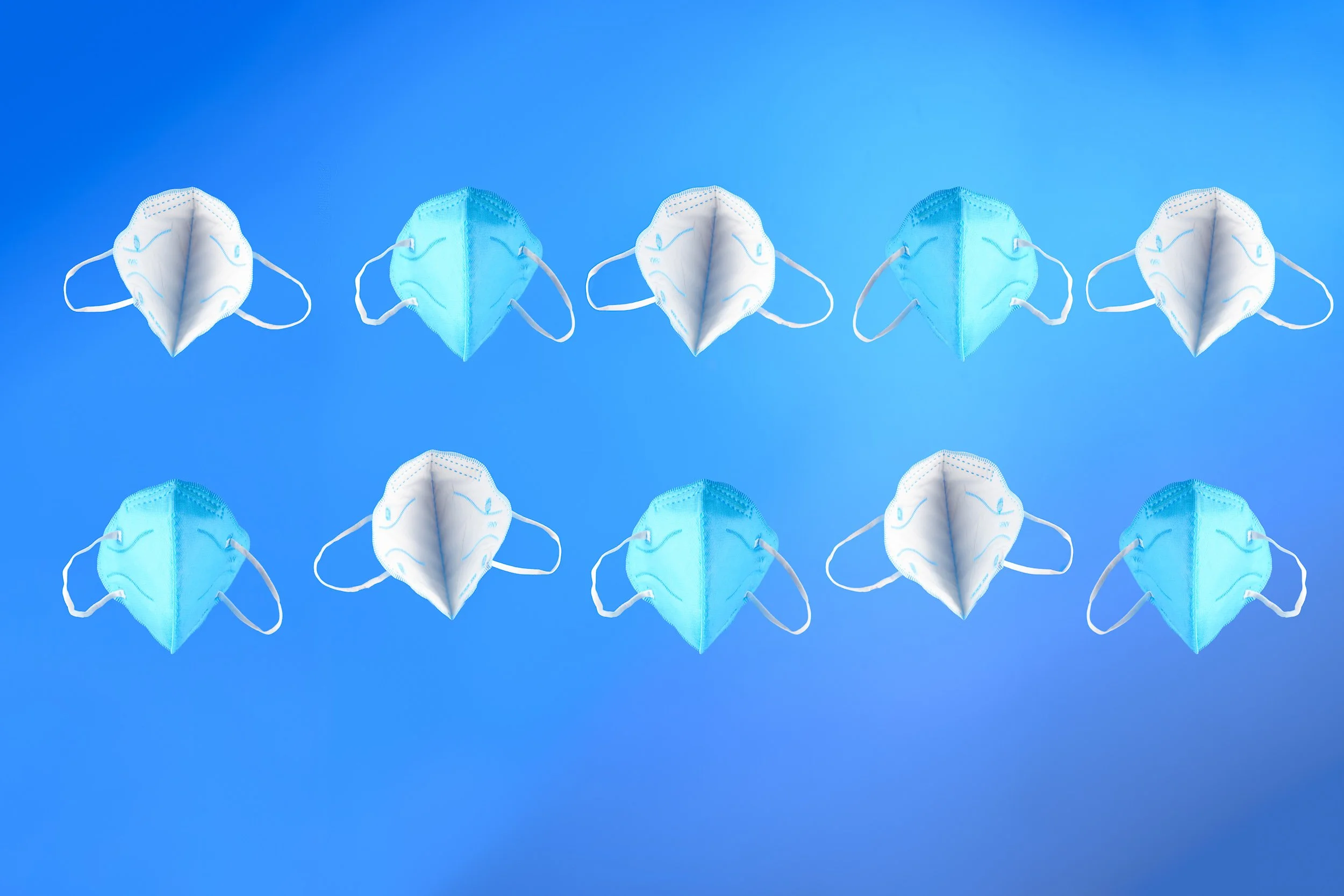 A set of protective face masks arranged in rows against a blue gradient background.
