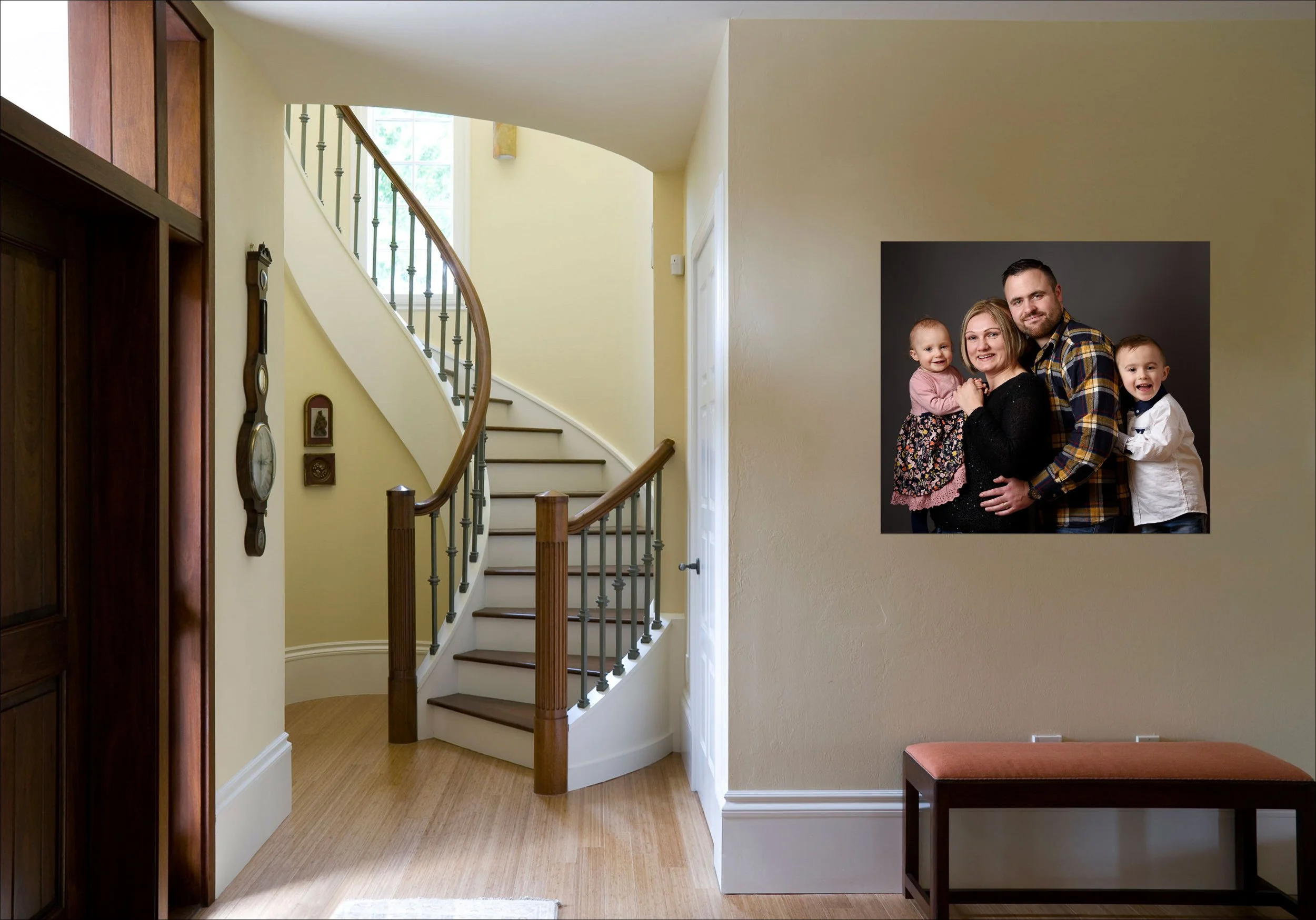 Interior hallway with staircase and framed family portrait displayed on the wall.
