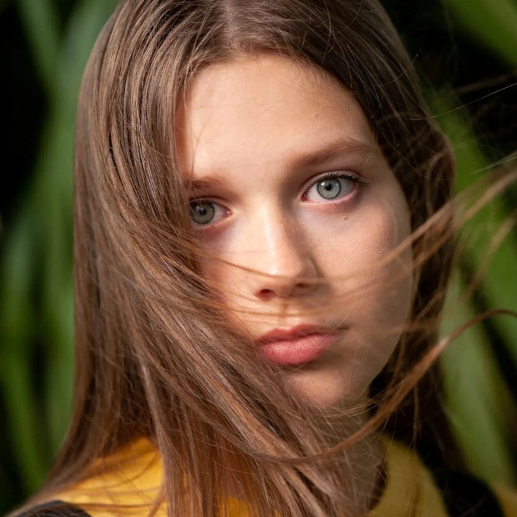 Portrait Photographer Ireland – young woman with long brown hair outdoors with natural green background