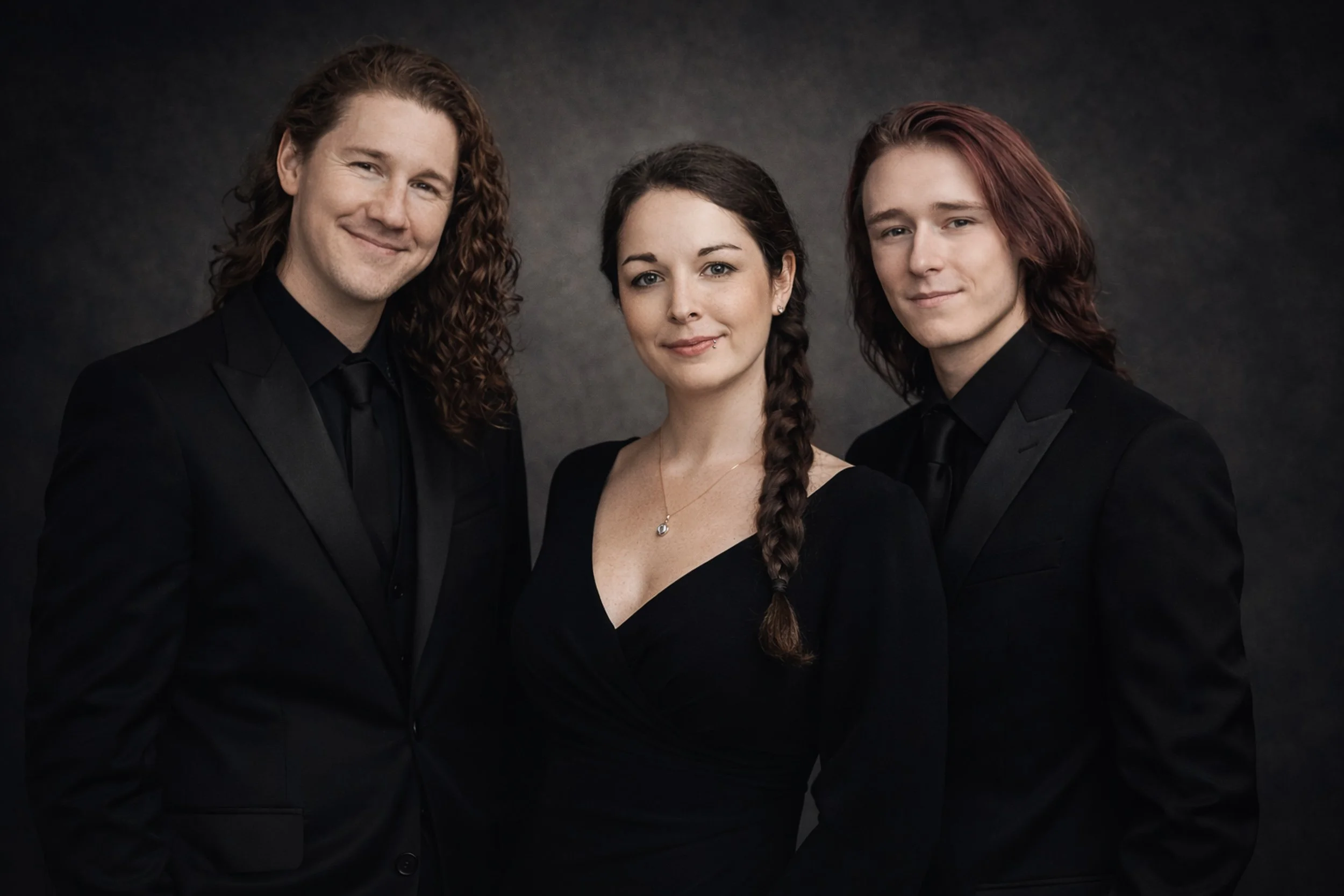 Portrait Photography Ireland – three people in the Ken Byrne Photography studio dressed in formal black attire against dark studio background