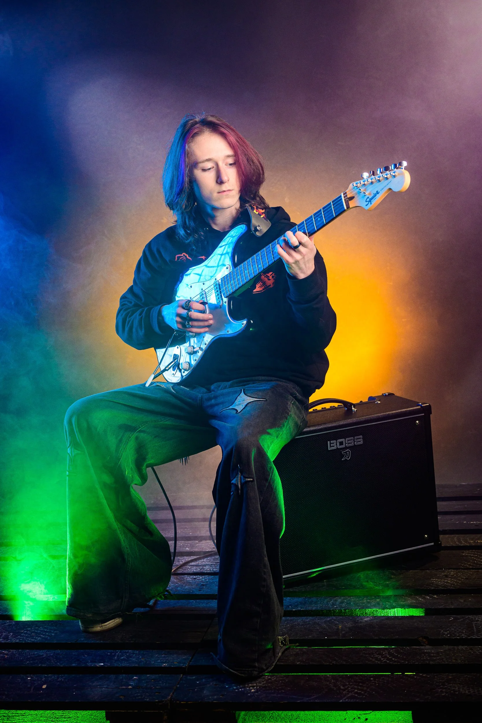 Studio portrait of a guitarist performing with vibrant lighting and amplifier setup