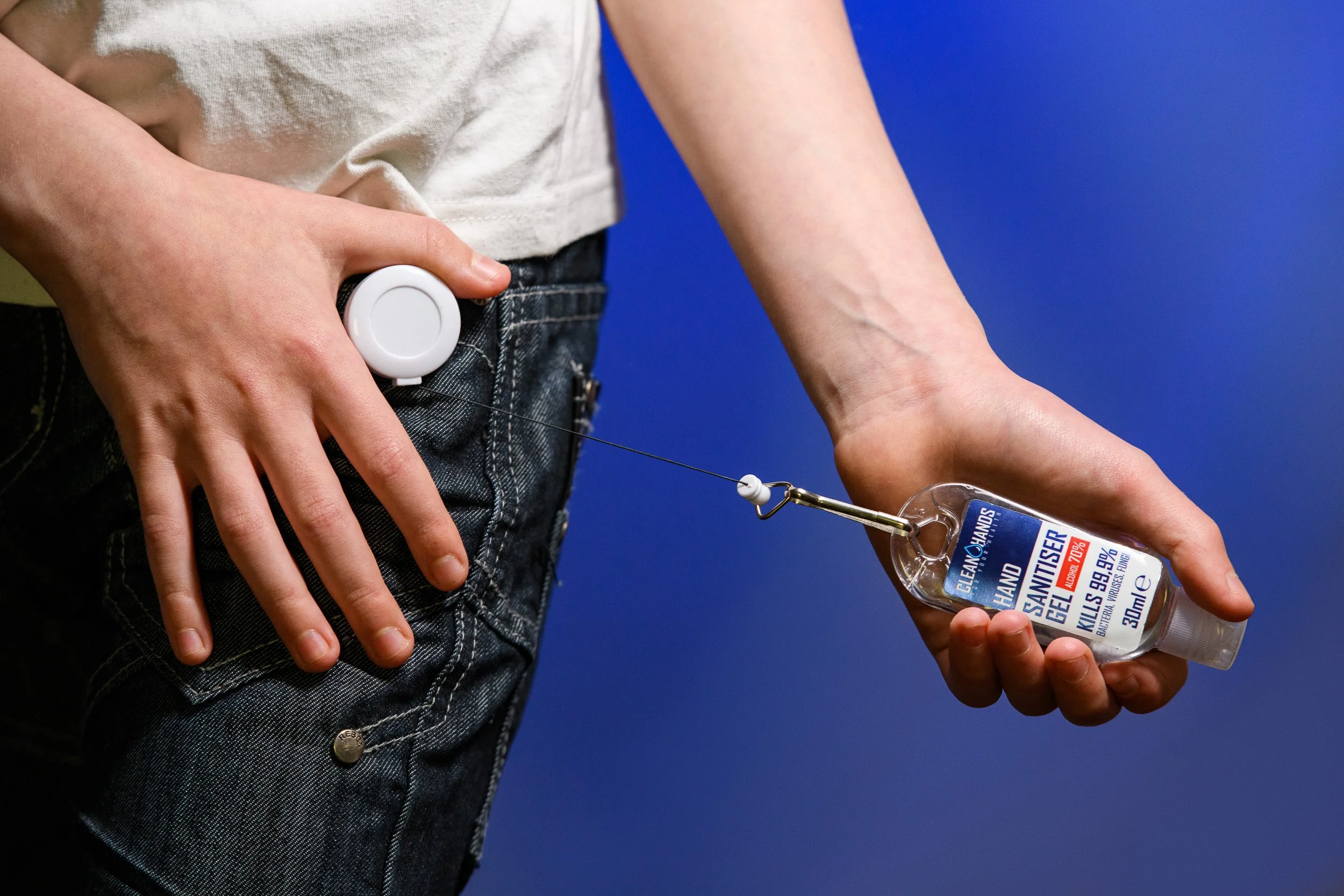 Close-up of a person using a hand sanitiser dispenser, pressing to release gel onto their hand.
