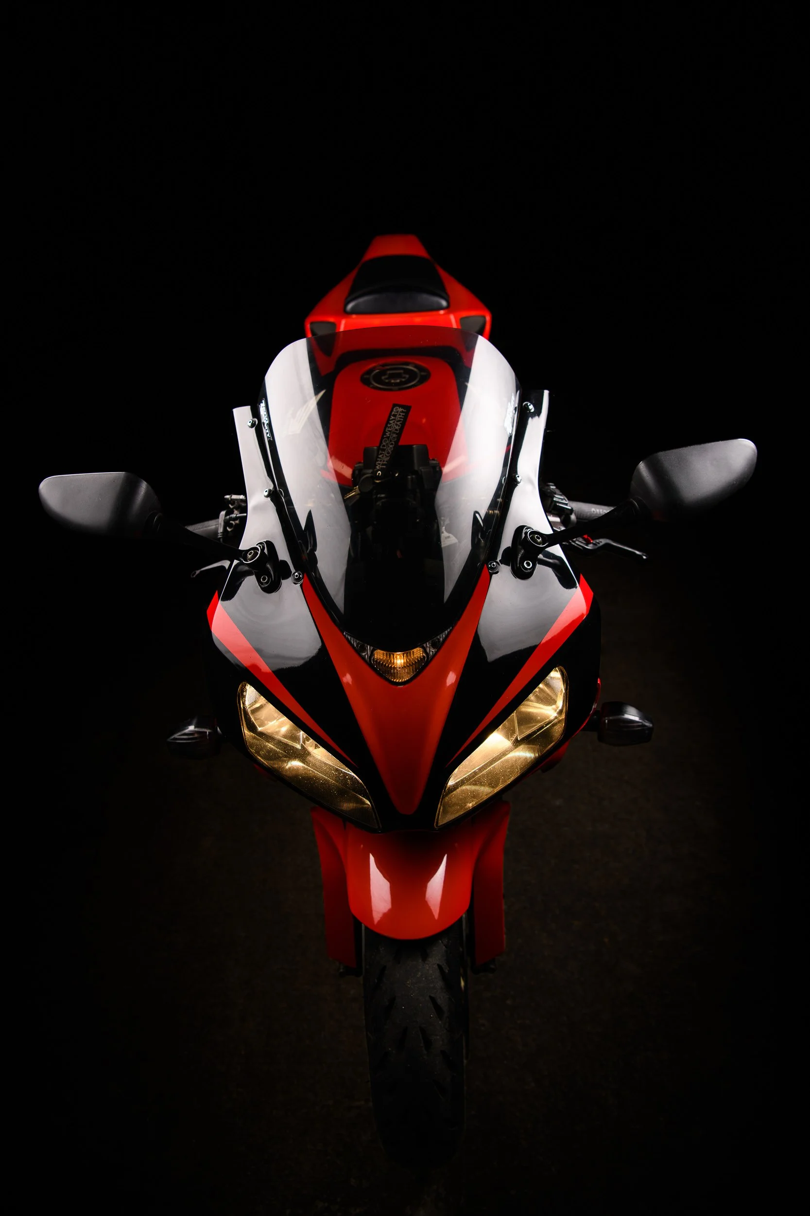 Front view of a red and white sport motorcycle positioned against a black background with studio lighting.
