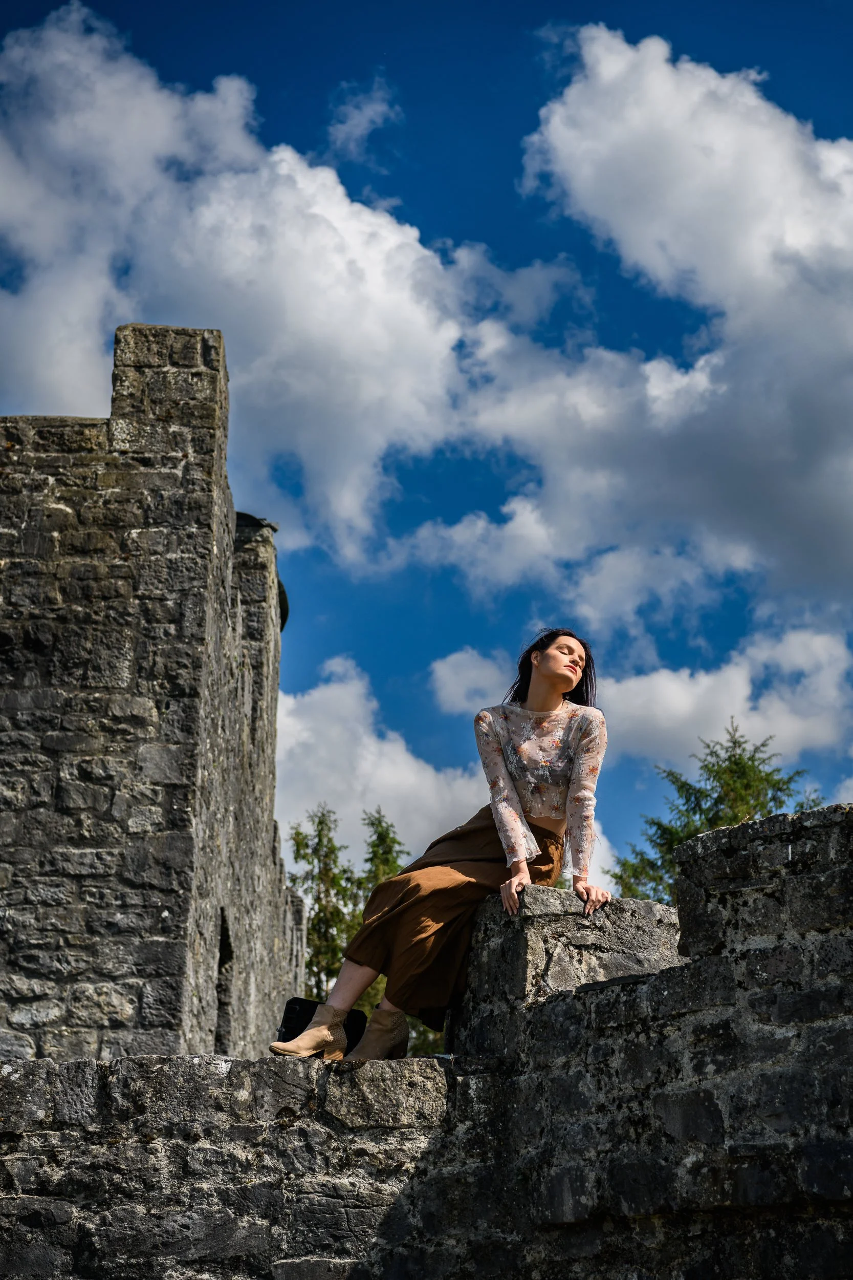 Editorial Portrait Photography Galway – woman seated on castle wall at Cloghan Castle