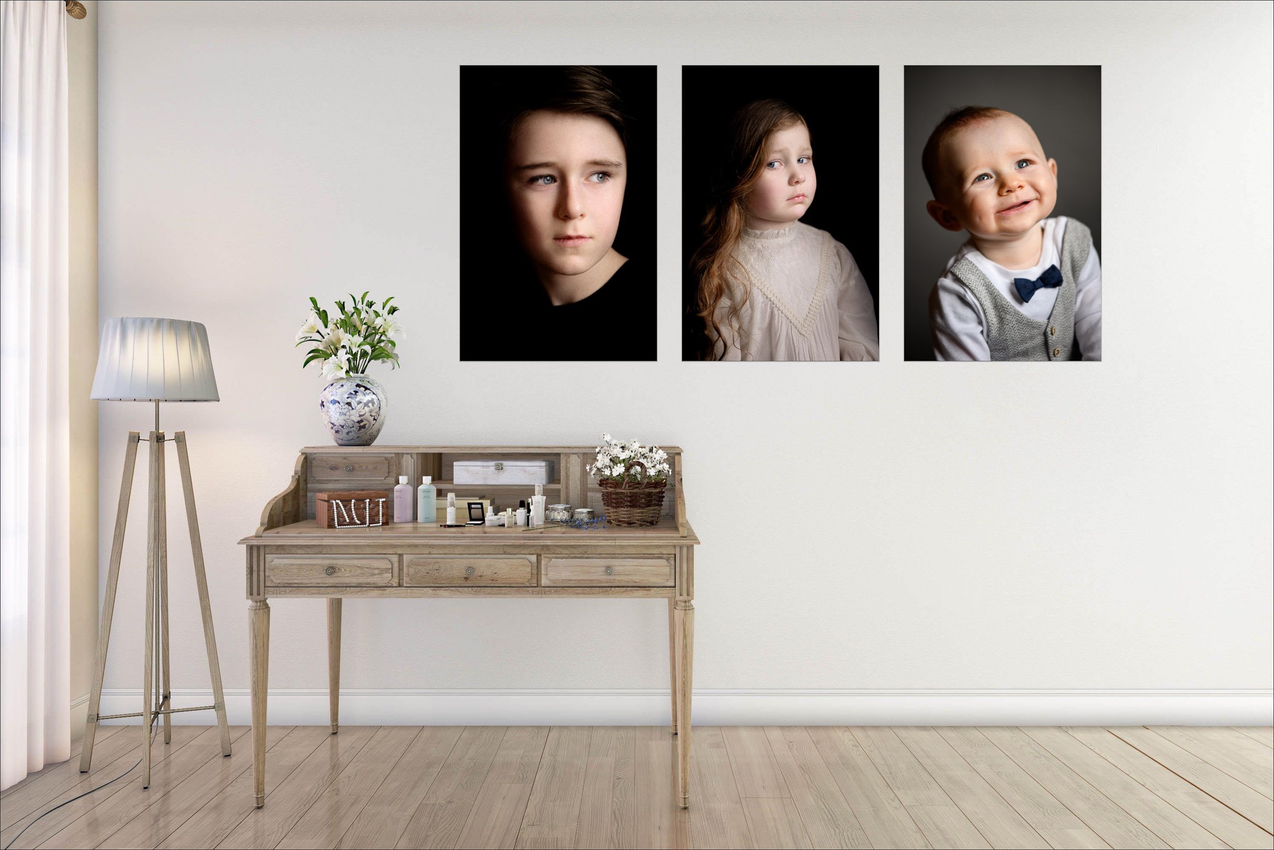 Three framed portrait photographs displayed above a wooden dresser in a softly lit room.
