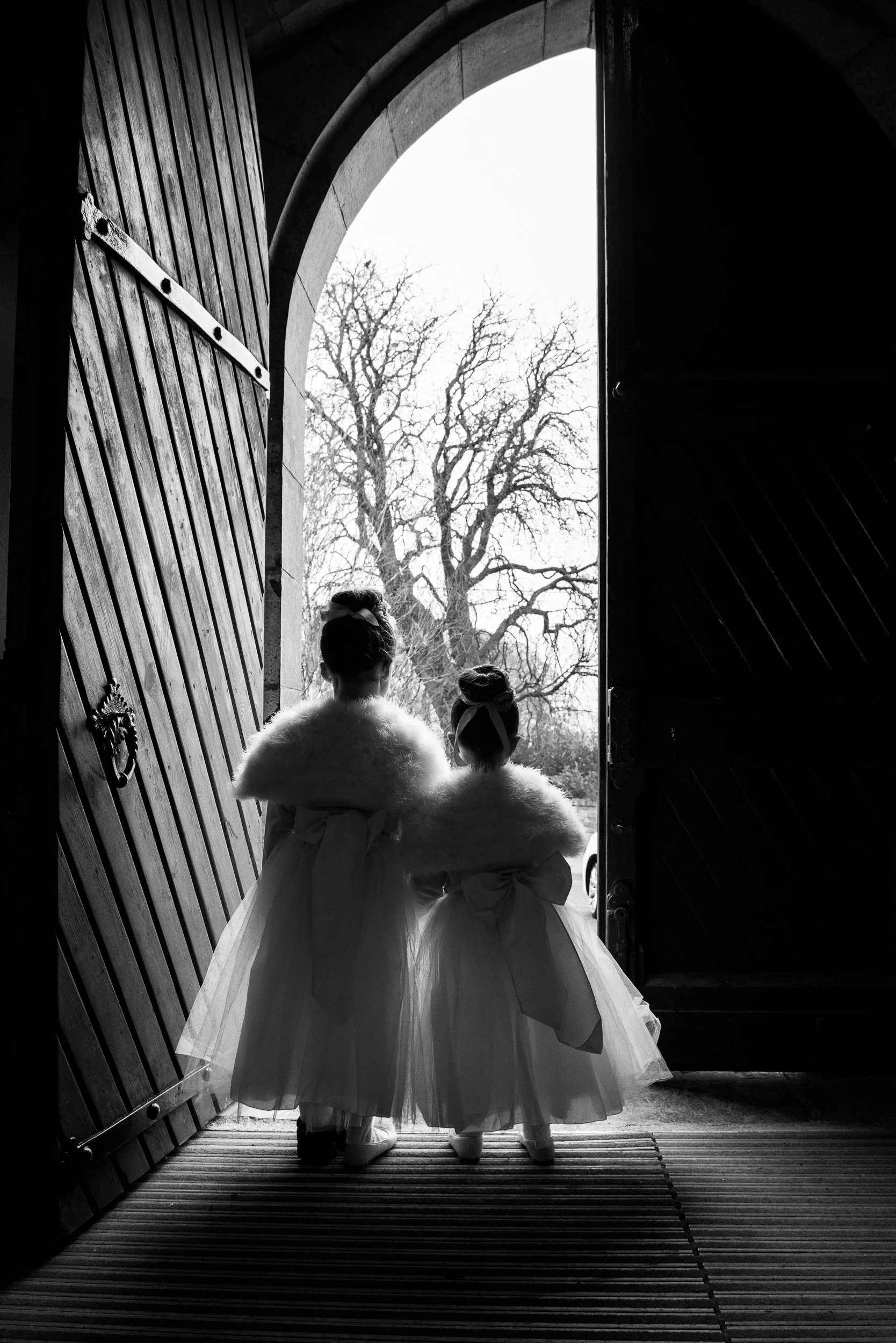 Wedding Photographer Ireland – flower girls waiting in church doorway with natural light at Castletown Geoghegan Church before the bride’s arrival