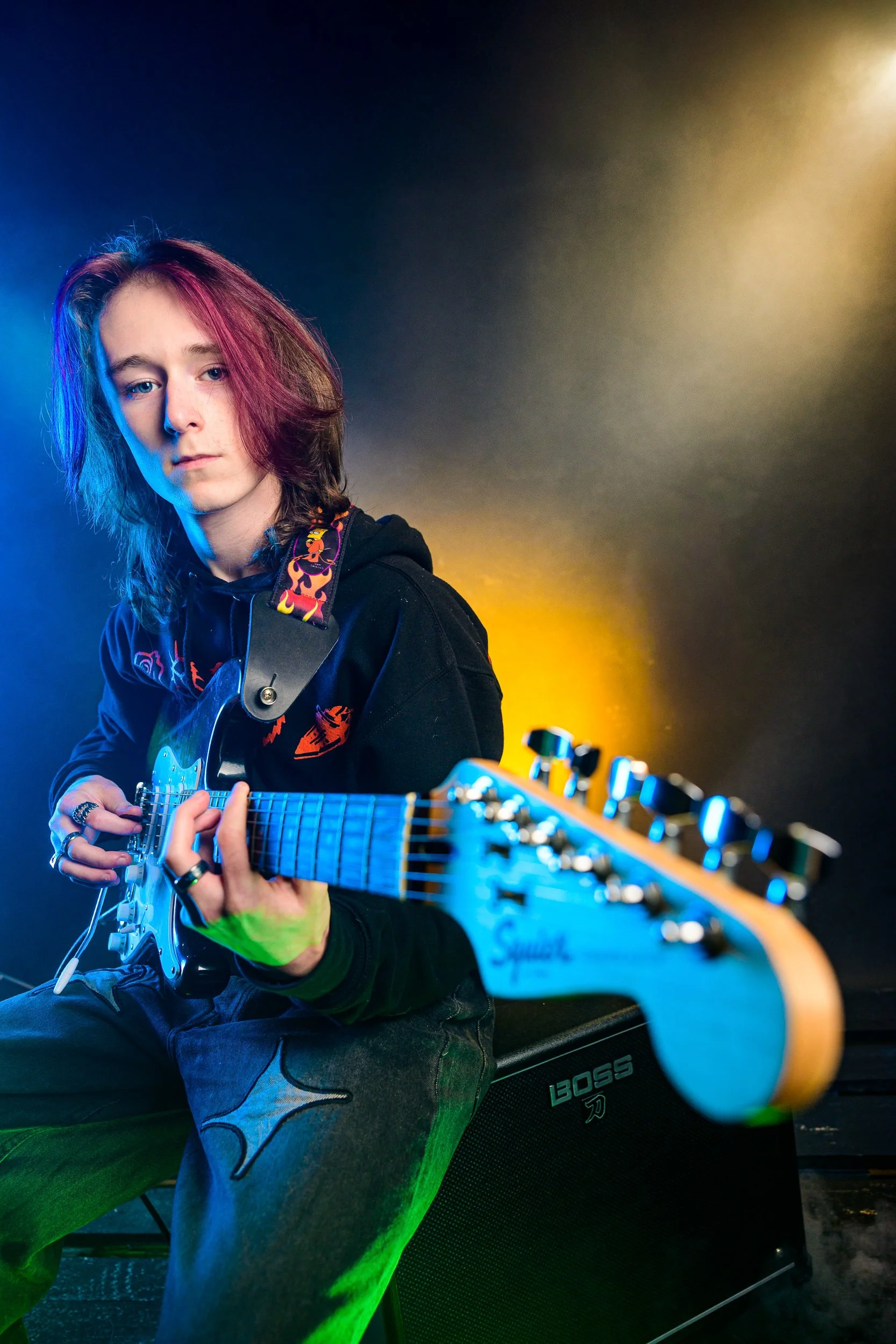 Creative portrait of a musician playing electric guitar with dramatic coloured lighting
