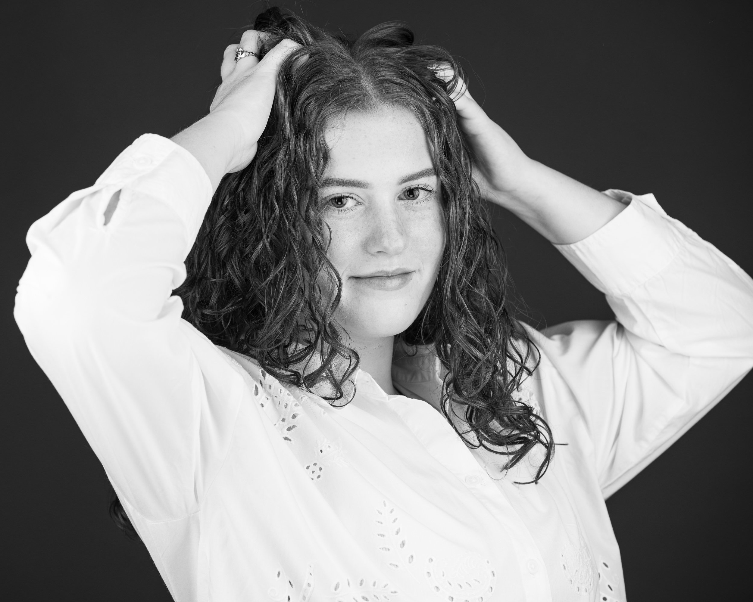 Studio portrait of a woman with curly hair posing against a dark background