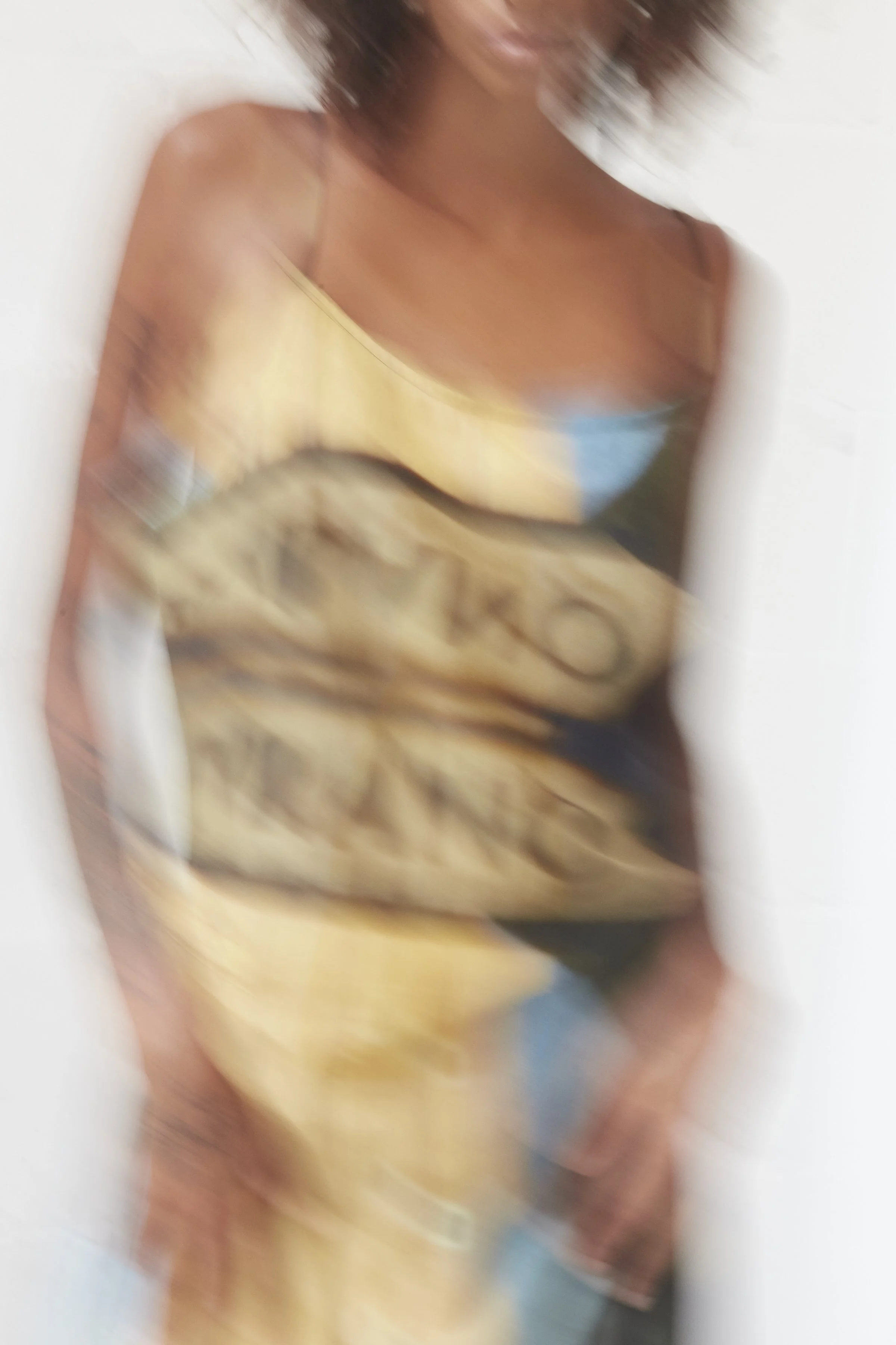 Motion-blurred campaign image of the Mouzáhres Murano Venezia wrap dress in multi with painterly signage-style print
