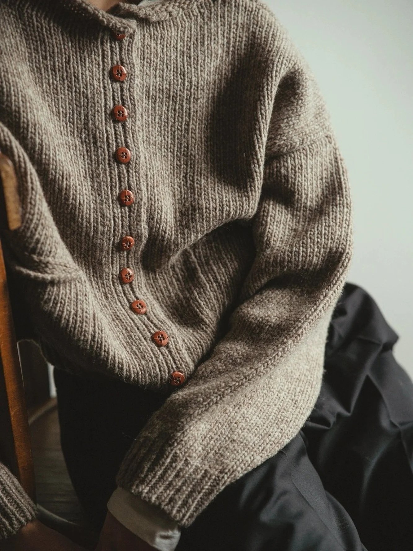 Model wearing the Stone Grey Pomba Cardigan by Floca, buttoned, with the sleeves falling past the wrists.