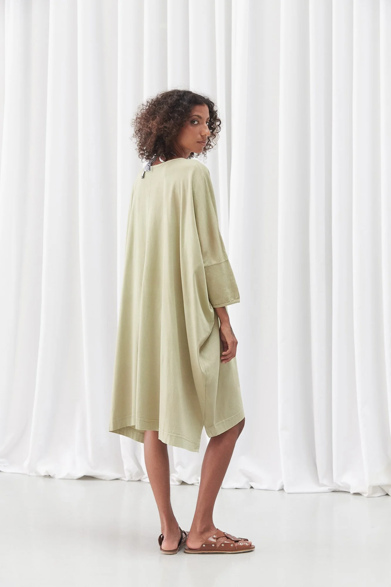 Model wearing the Cordoa Muscari brown sandals with an Intellectual Leisure green dress, full-length side view