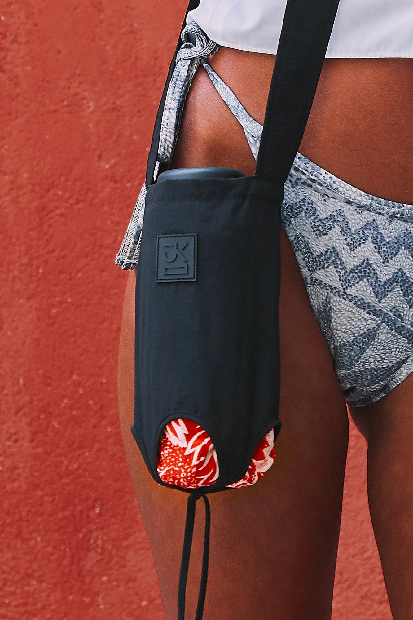 J.Kim Bukhara water bottle pouch in black, close-up of the crossbody bottle holder with adjustable strap and floral trim detail