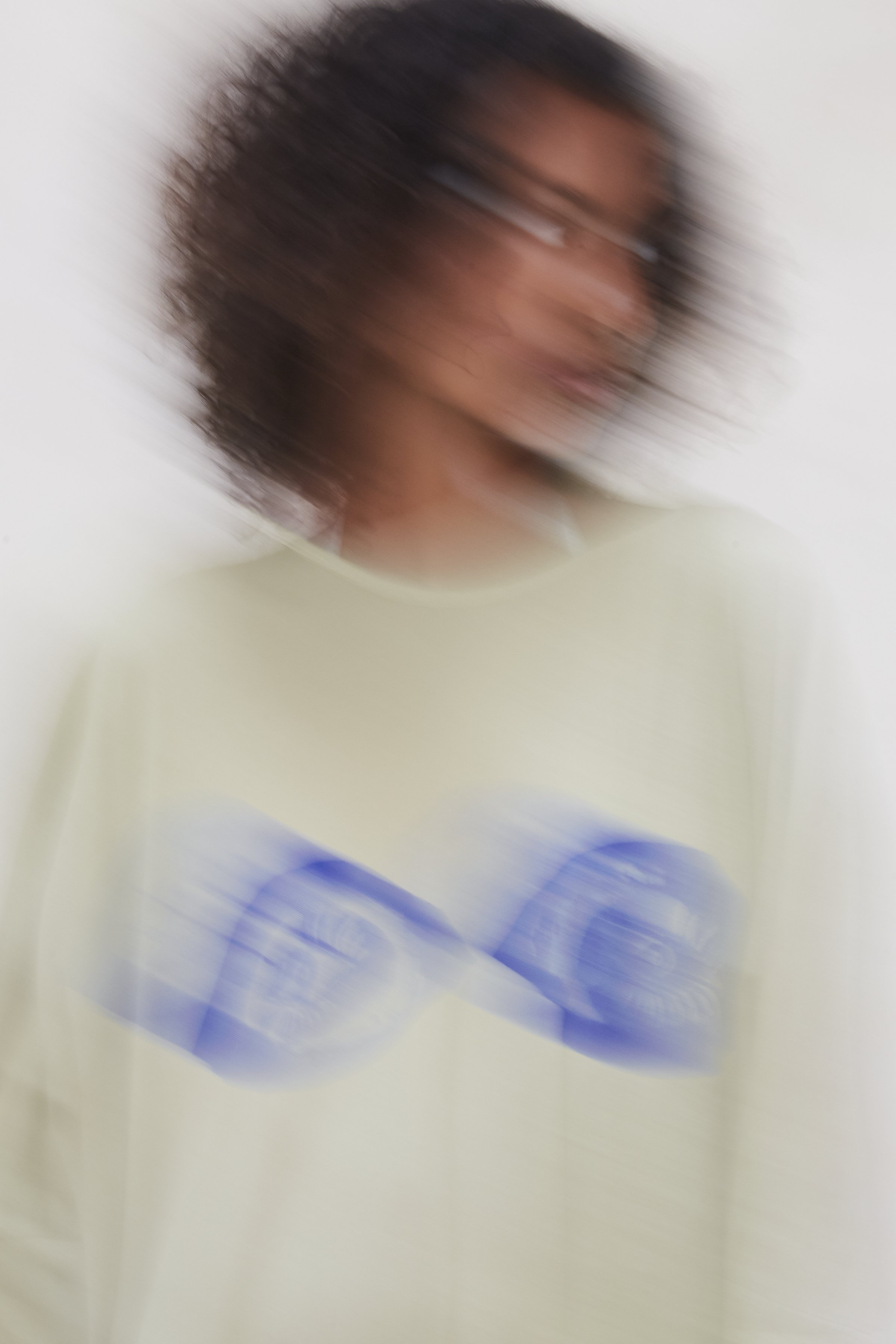 Motion-blurred campaign image of the Intellectual Leisure Big Greek T-dress in green with blue eyes print