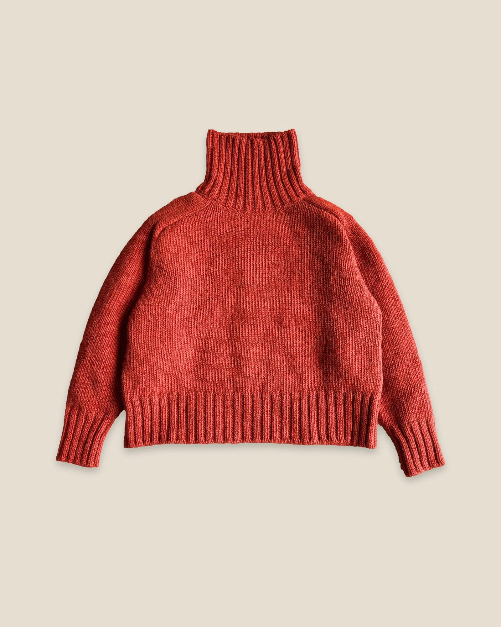 Floca Ringo Sweater in paprika, laid flat, with the turtleneck standing up and ribbed cuffs and hem
