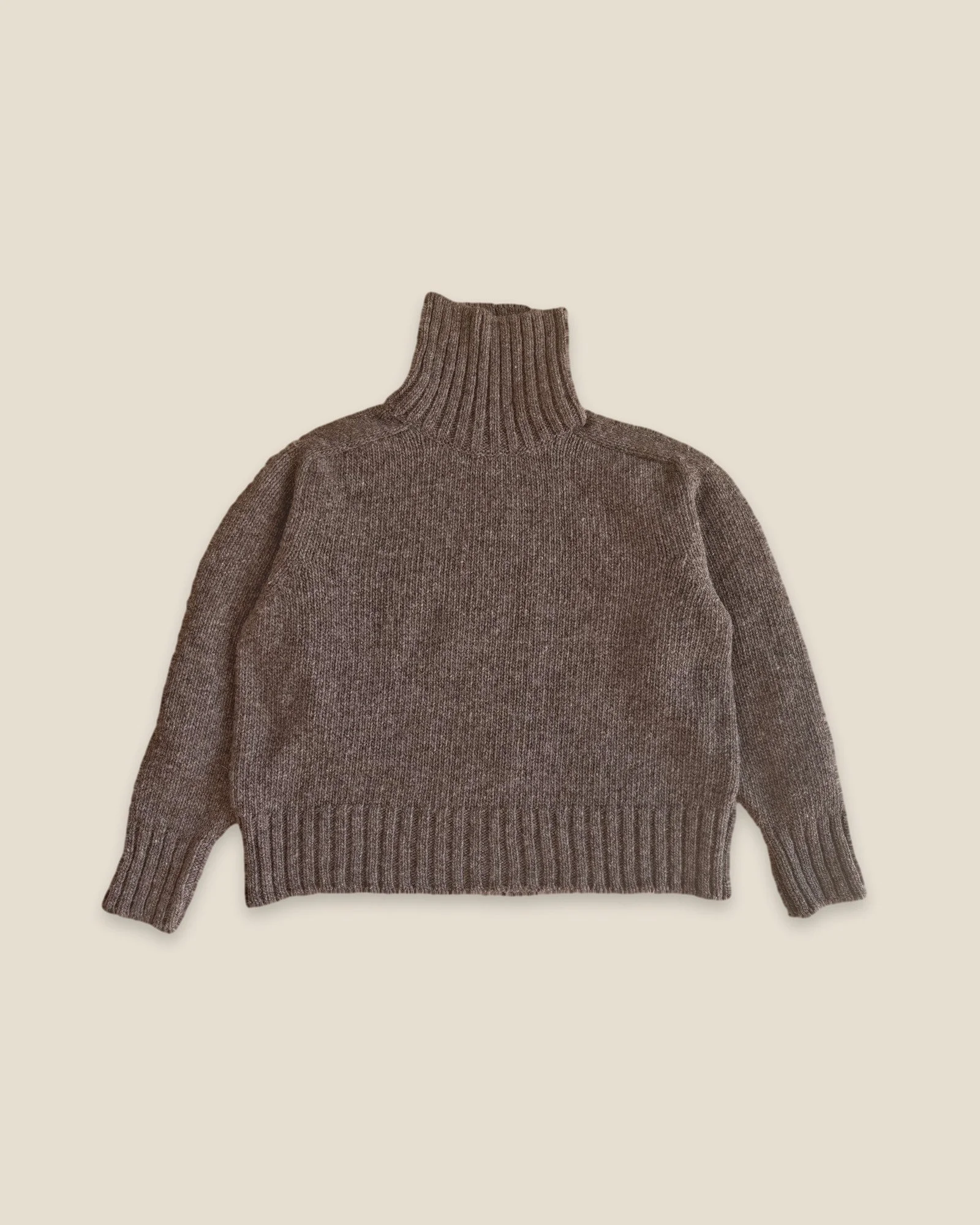Woodsmoke Ringo Oversize Sweater by Floca, handcrafted in Galicia from Spanish wool, laid flat with the tall turtleneck up and ribbed cuffs and hem.