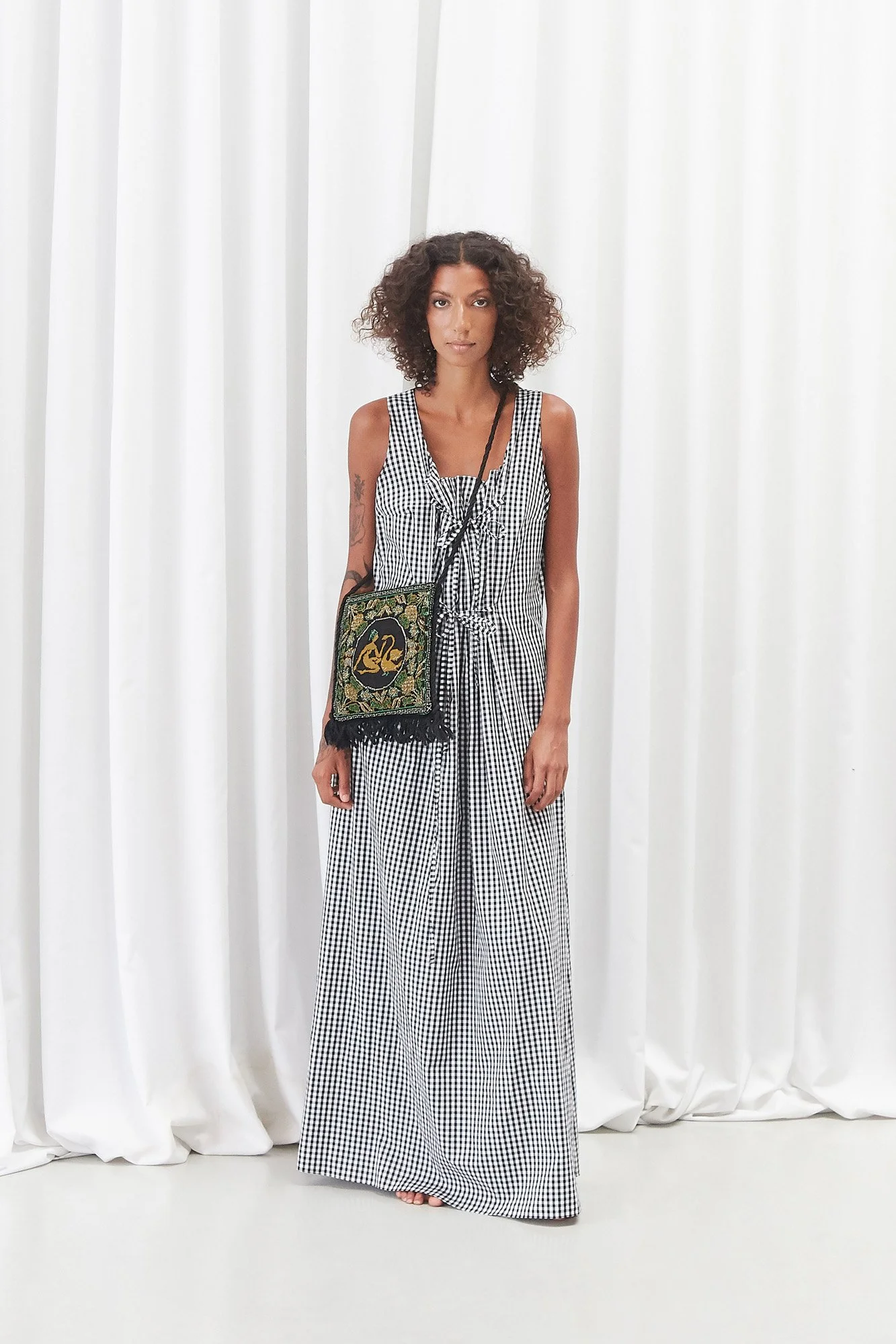 Model wearing the Vestral Collected Leda satchel bag as a crossbody, full-length front view styled with styled with an Intellectual Leisure black and white check dress