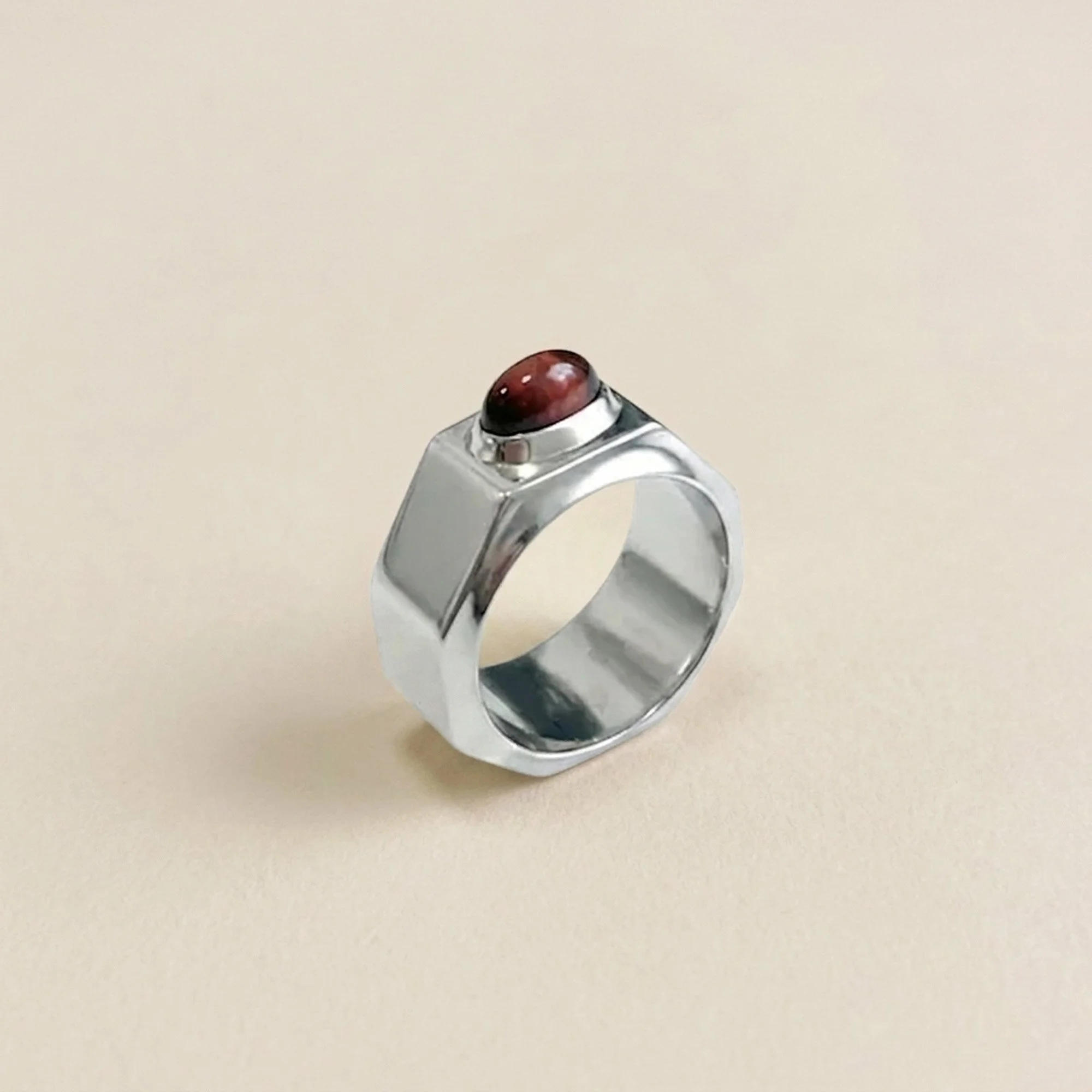 Three-quarter view of the Florence Moorhead Boulon Ring showing its wide faceted hexagonal band and red tiger’s eye cabochon in a raised bezel.