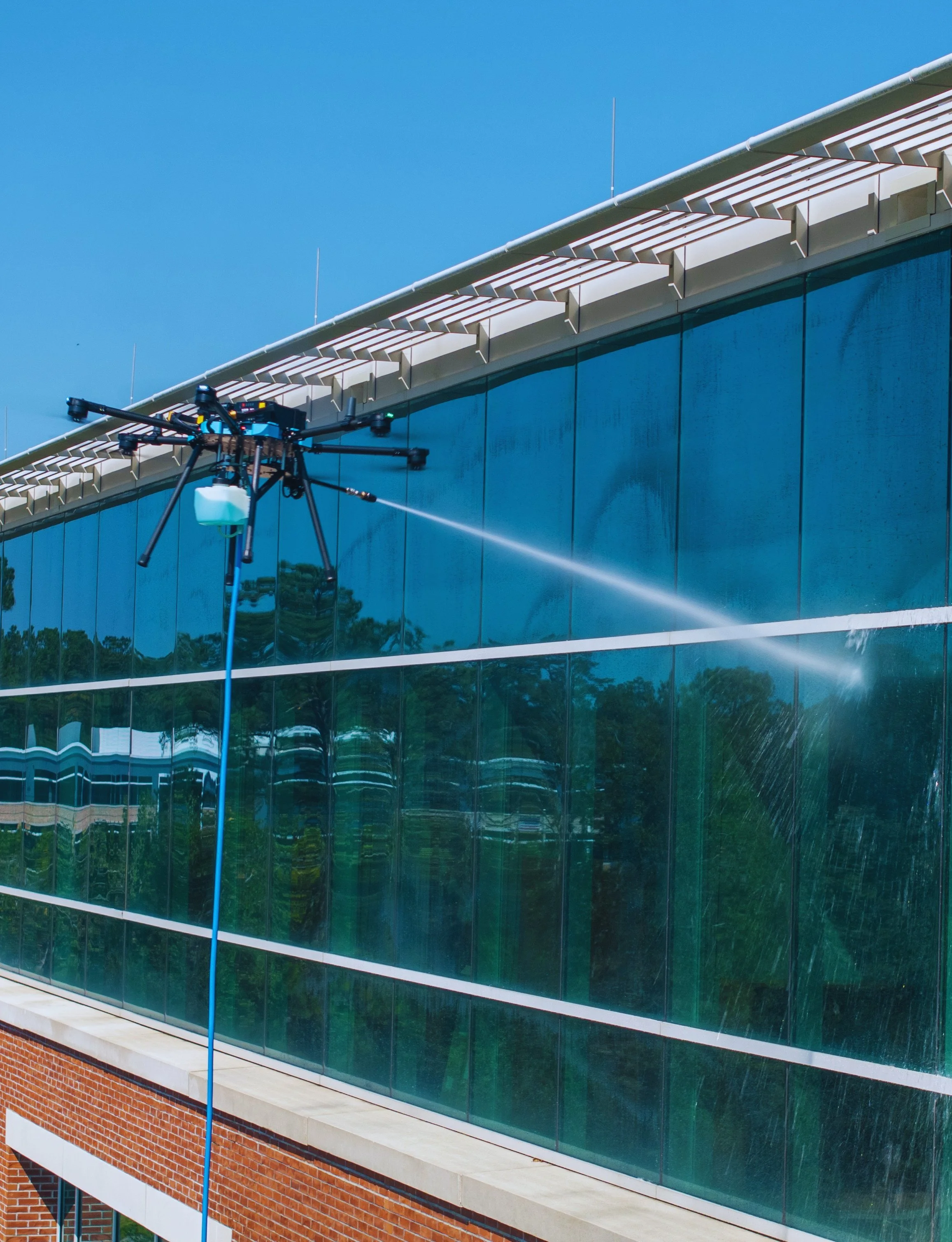 Drone with Honey Do Exterior Cleaning soft washing glass windows on a multi-story commercial building in Central Florida, providing safe, efficient, no-lift exterior cleaning for property managers and large facilities.
