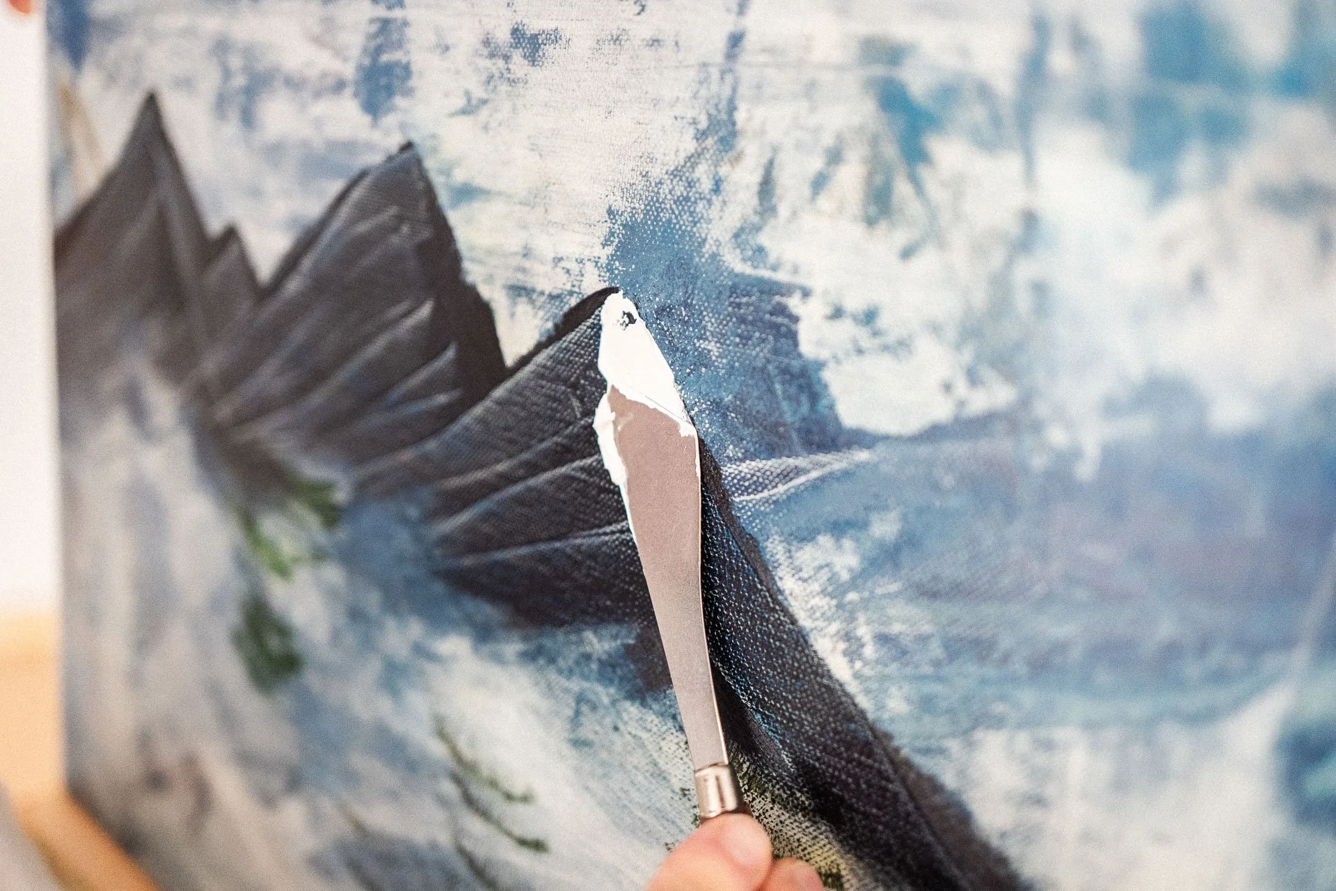 Maler, der mit einem großen Pinsel eine Landschaft auf eine Leinwand malt, Himmel und Berge sichtbar.