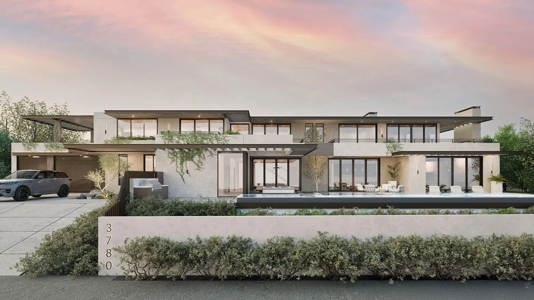 Modern multi-story house with large glass windows and outdoor areas. The house features a flat roof, outdoor seating, a swimming pool, and landscaping with shrubs and small trees. The sky is pink and purple, suggesting sunset or dawn.